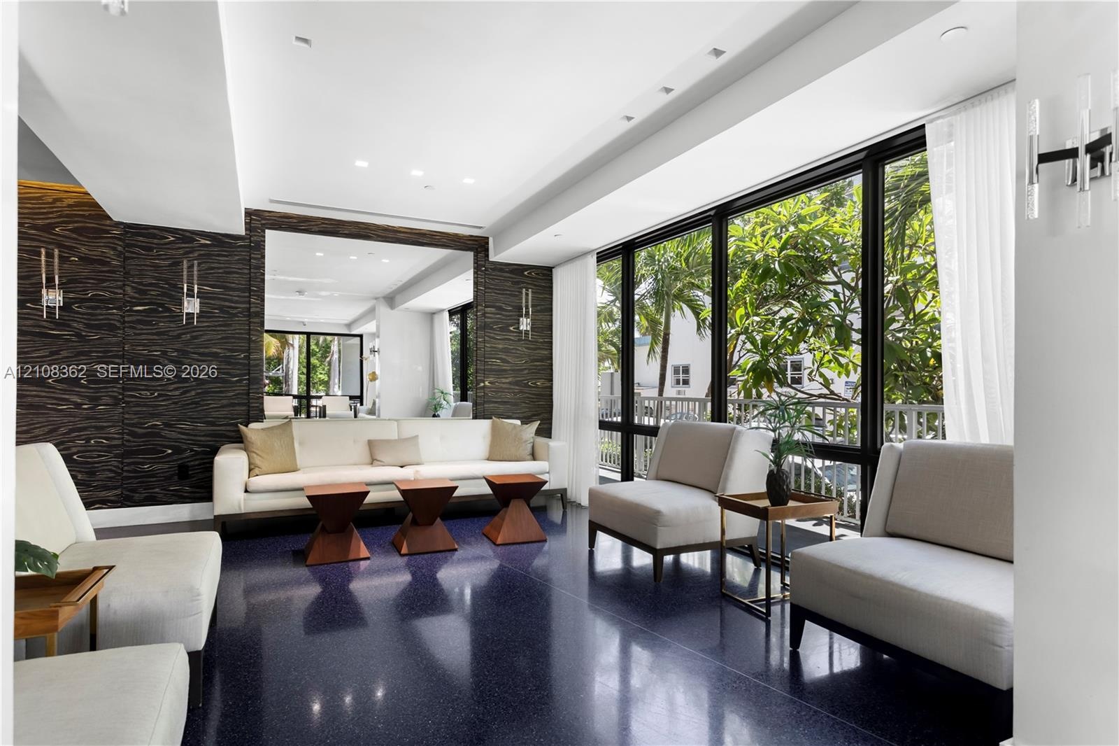 Interior space featuring floor-to-ceiling windows, dark high-gloss flooring, recessed lighting, wall-mounted light fixtures, and dark-toned textured w