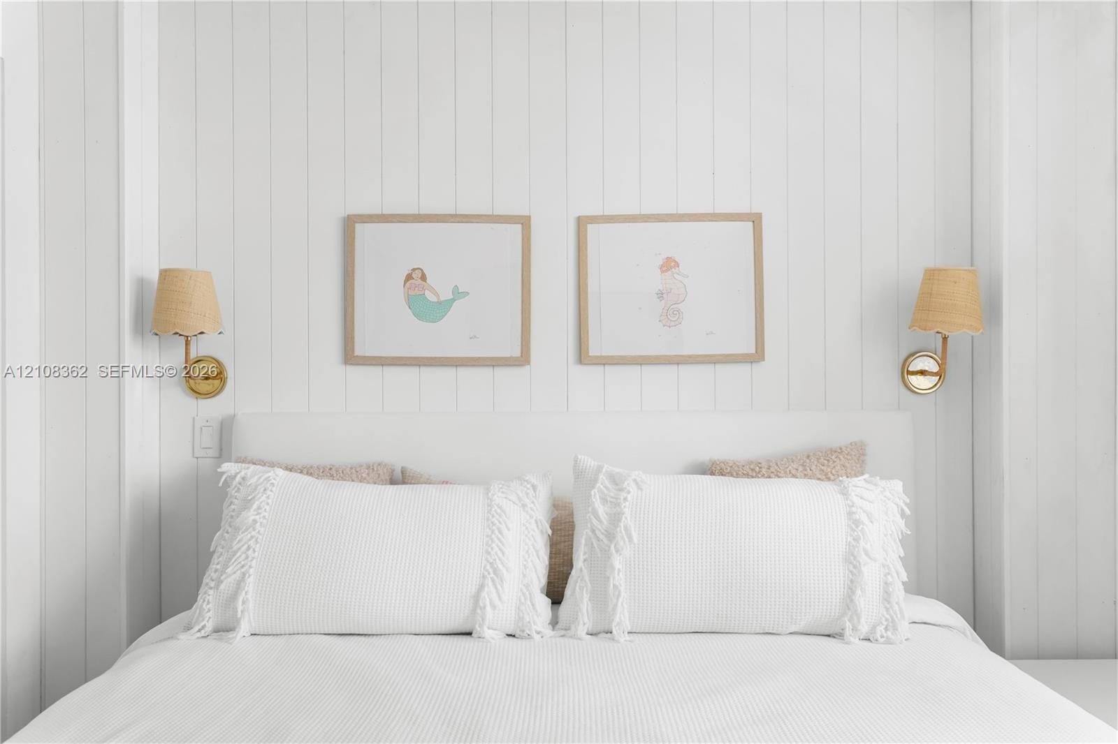 Vertical plank wood wall paneling with dual brass-finish wall-mounted sconces featuring textured shades