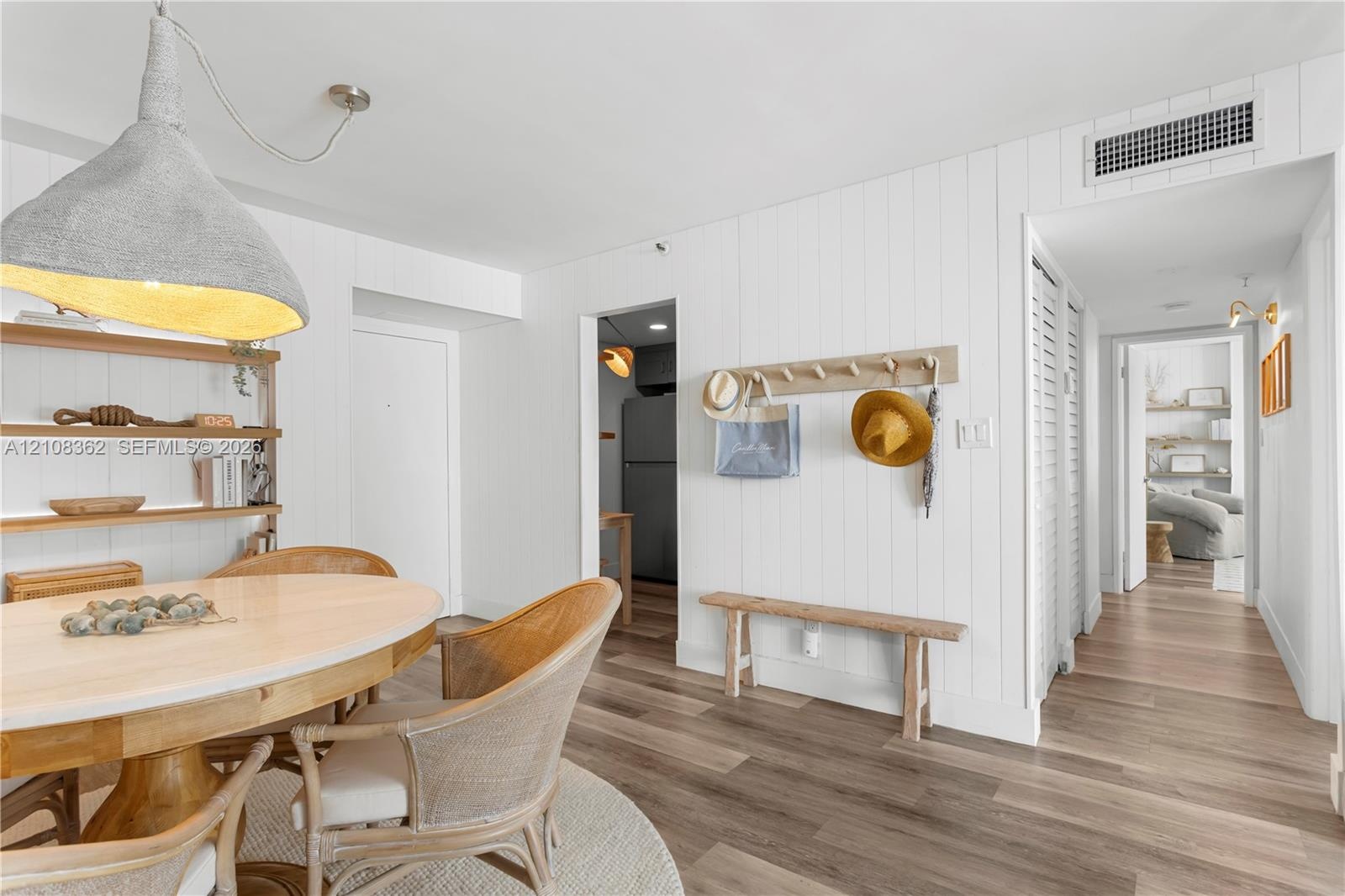 Vertical wood-plank wall paneling, wide-plank wood-finish flooring, built-in open shelving, and a large metal dome pendant light