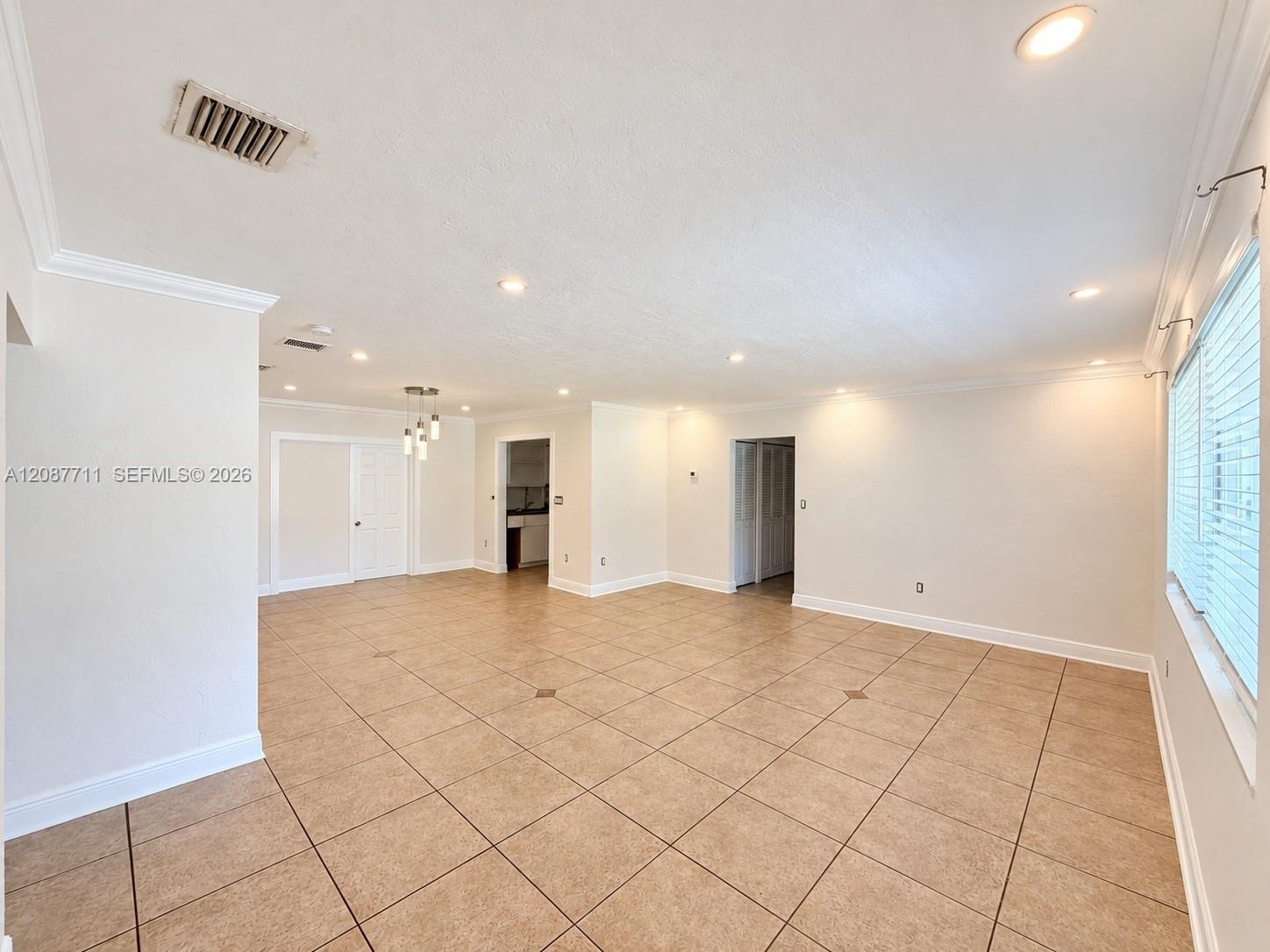Open-concept interior featuring large-format ceramic tile flooring, neutral wall tones, recessed lighting, and multi-light pendant fixture