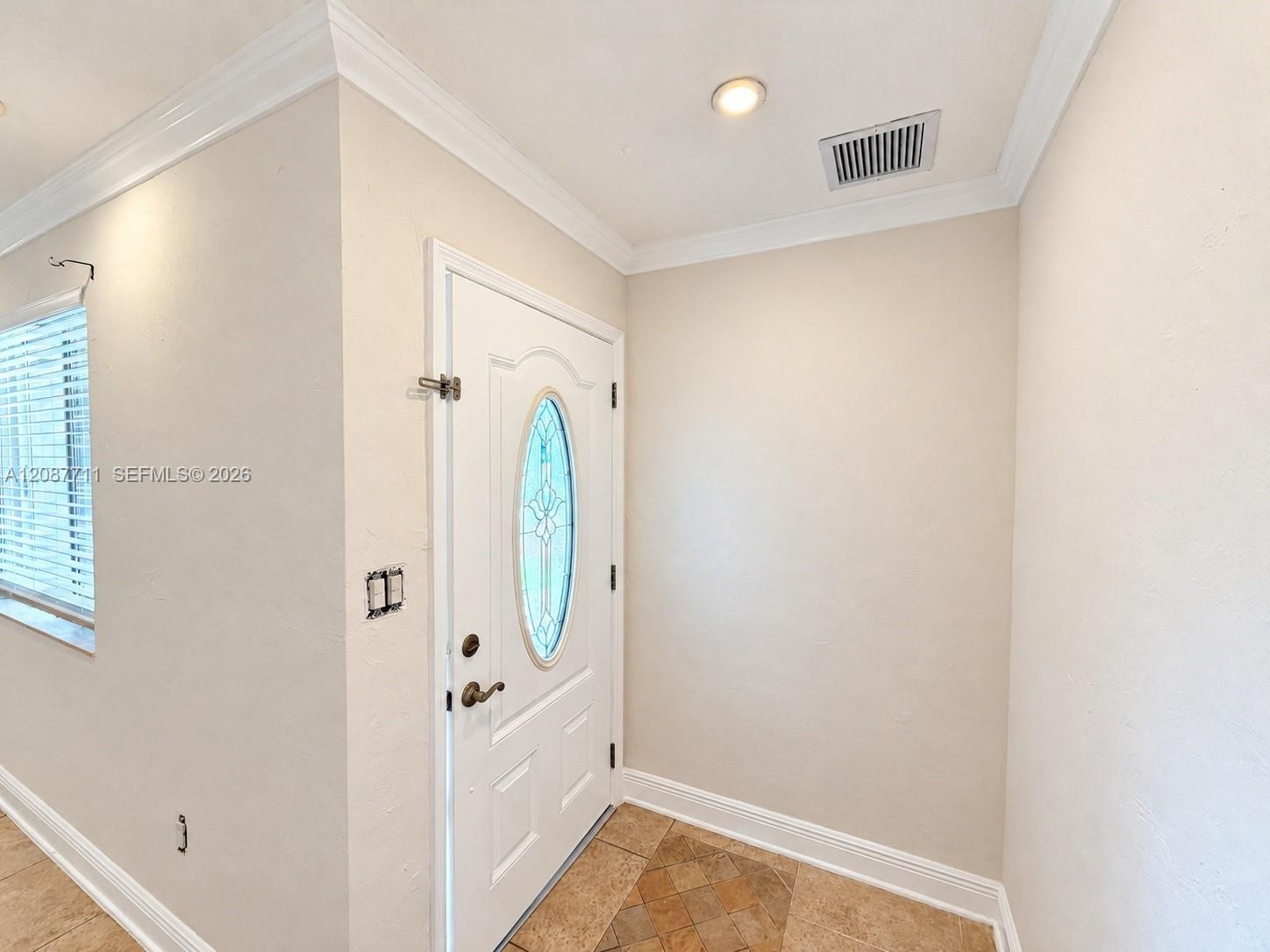 Entryway featuring a white door with an oval glass insert, recessed lighting, crown molding, and stone tile flooring