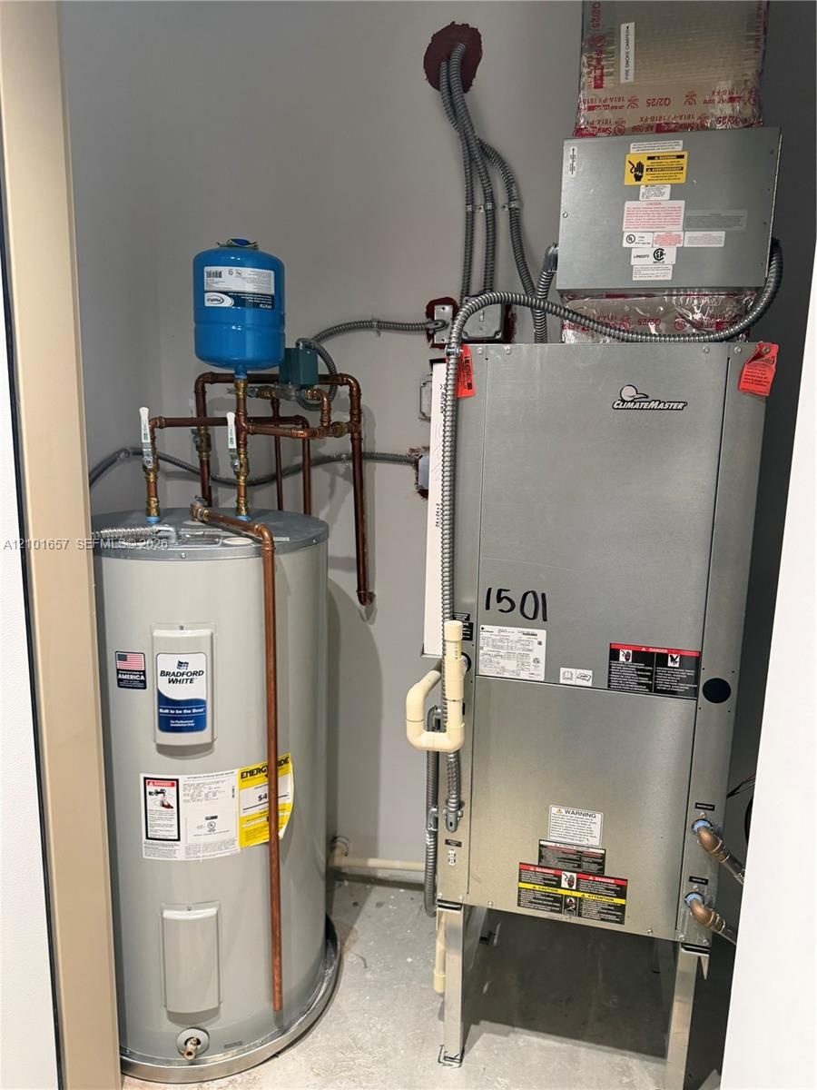 Mechanical utility closet containing a ClimateMaster geothermal heat pump, a Bradford White electric water heater, and a thermal expansion tank with i