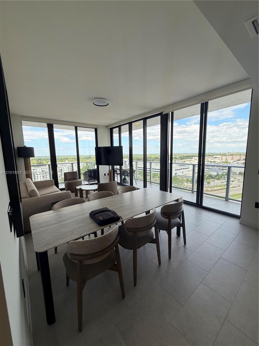 Floor-to-ceiling windows with panoramic exterior exposure, tile flooring, and access to a private balcony