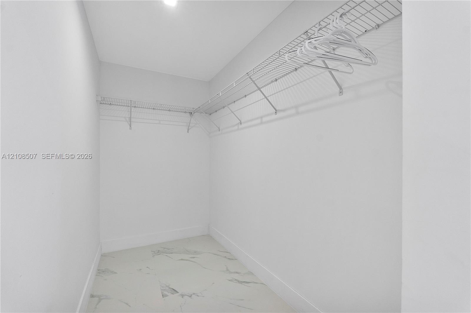 Walk-in closet featuring stone-patterned tile flooring and wrap-around wire shelving