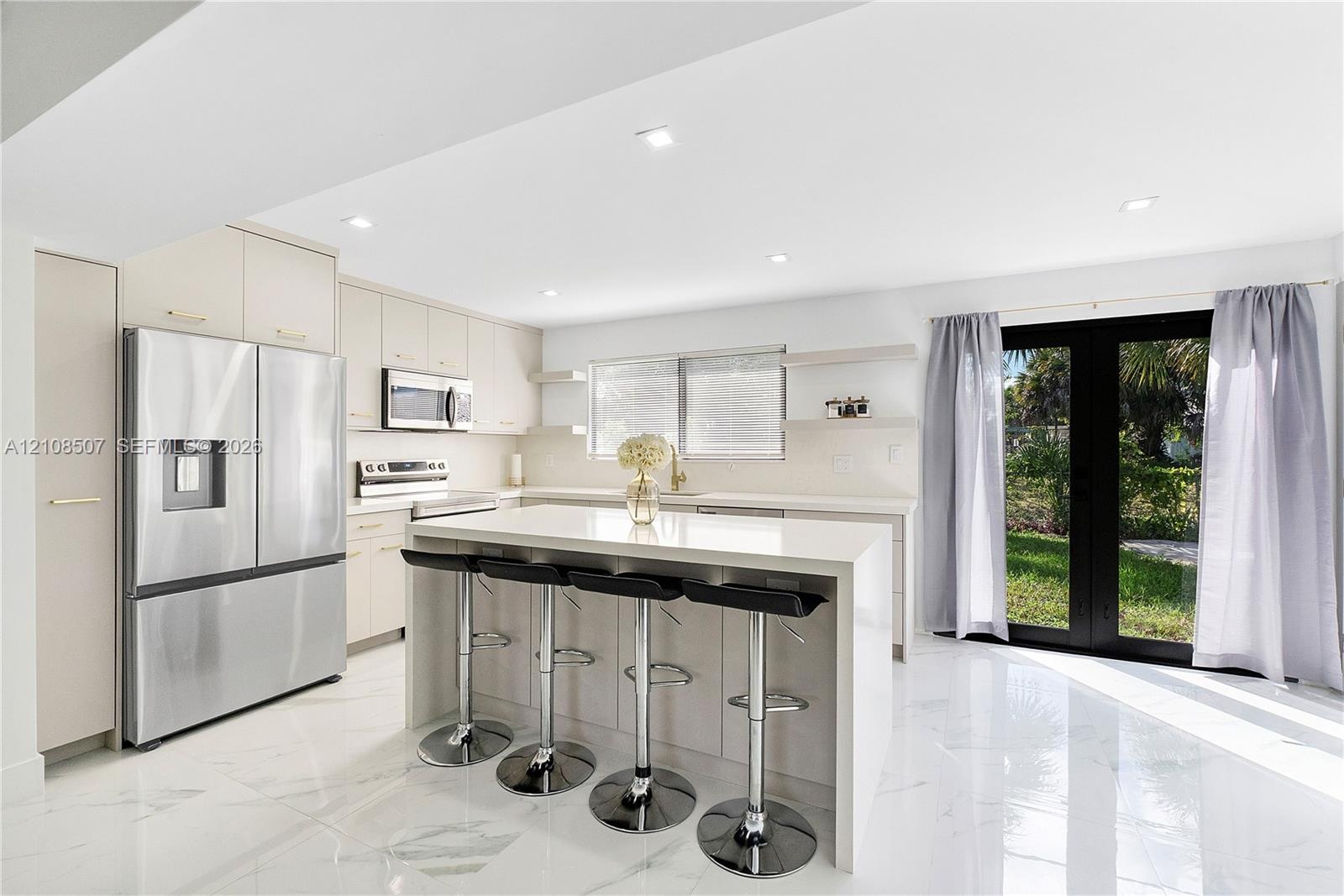 Kitchen featuring a center island with quartz countertop, stainless steel appliances, flat-panel cabinetry, recessed lighting, and large glass-panel d