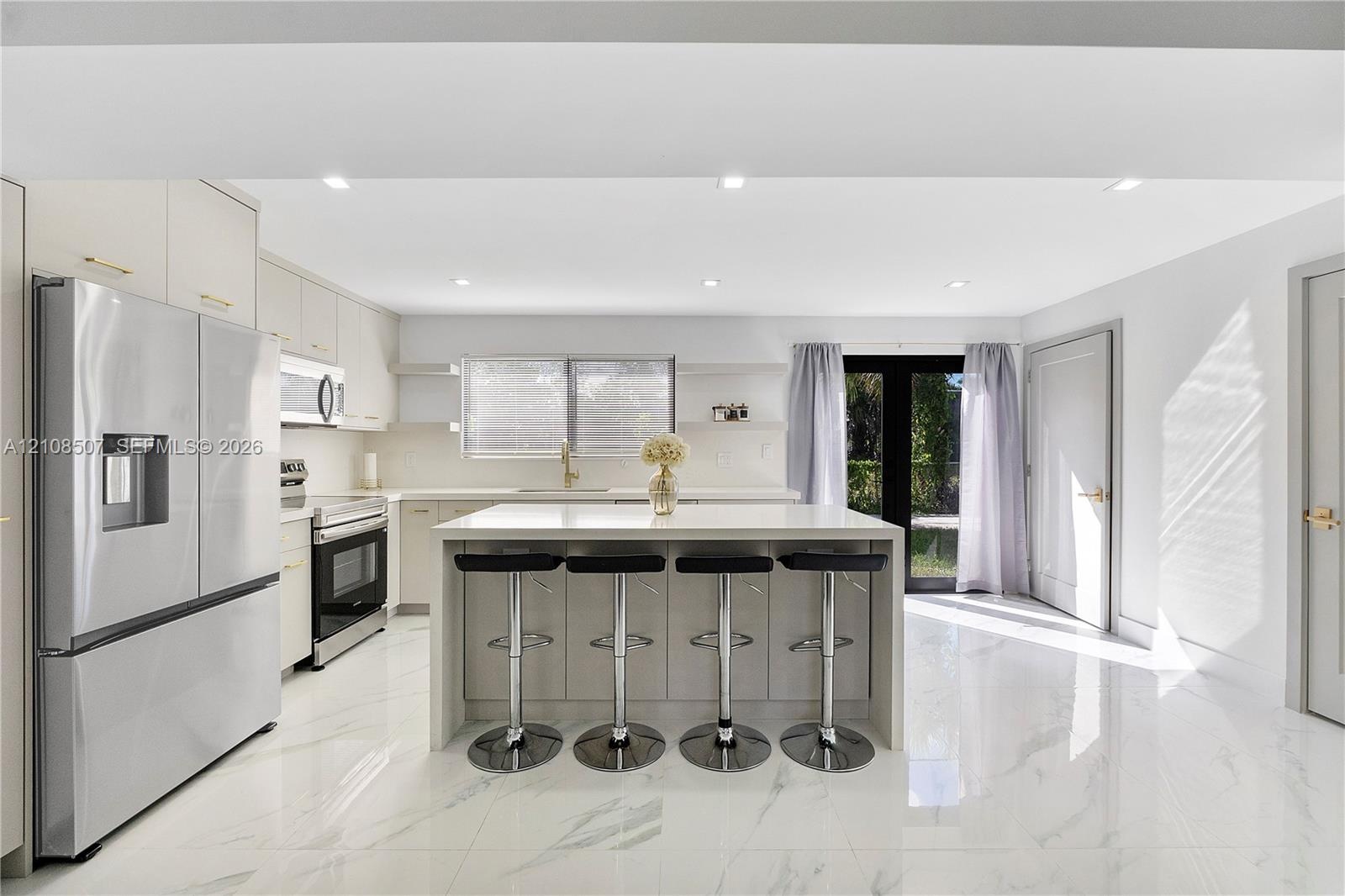 Kitchen featuring white cabinetry, a center island with a stone-finish countertop, stainless steel appliances, recessed lighting, and large-format til