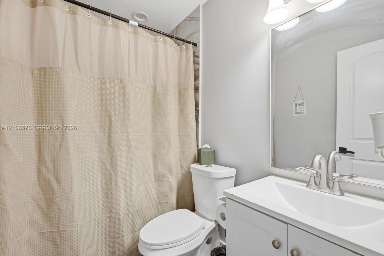 Bathroom featuring a white vanity cabinet with an integrated sink, polished chrome faucet, full-width mirror, and multi-bulb vanity lighting
