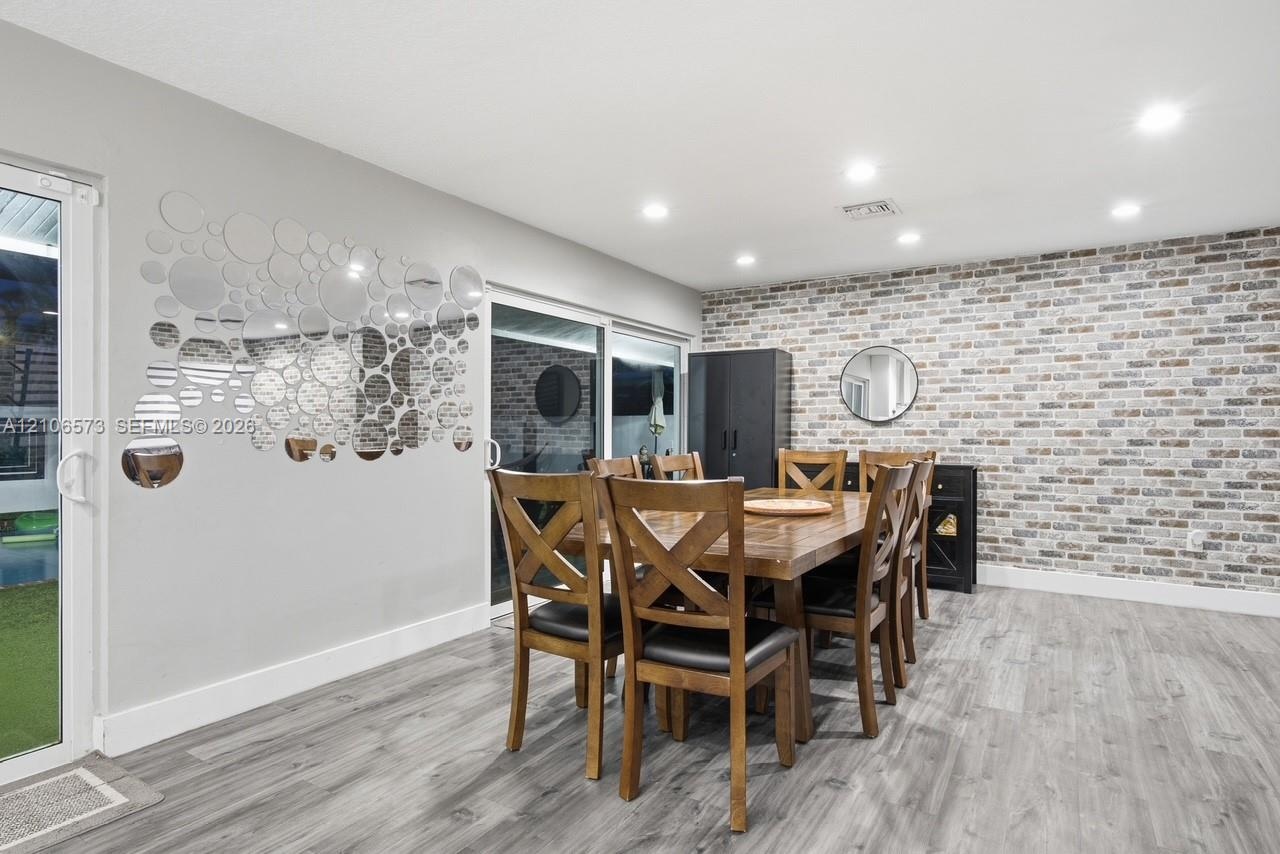 Textured brick accent wall, wood-finish flooring, recessed lighting, and sliding glass door