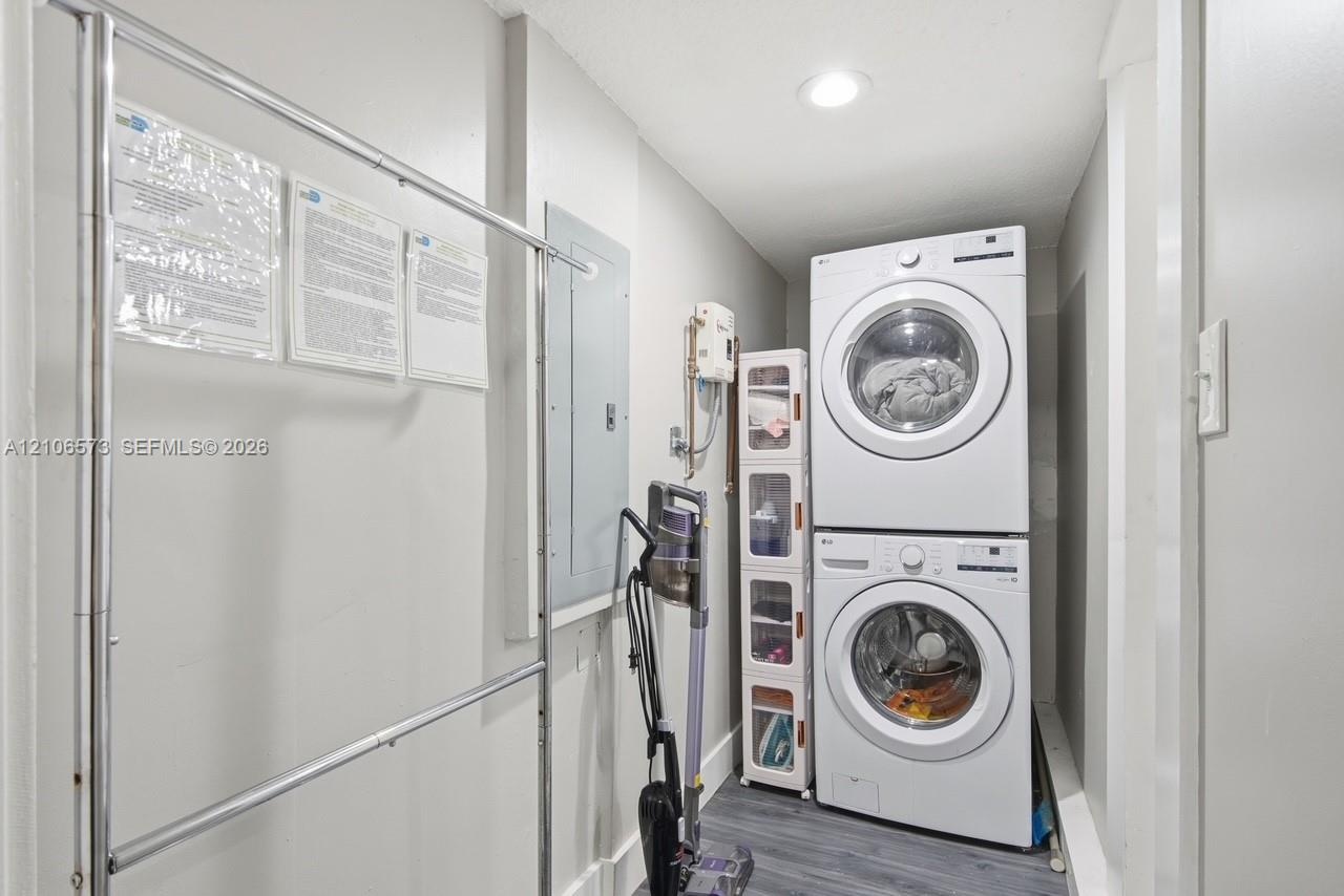 Laundry space featuring a stacked washer and dryer unit, recessed lighting, and wood-finish flooring