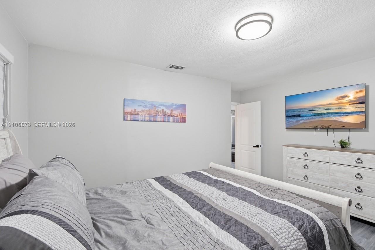 Neutral-toned interior featuring smooth-finish ceiling, flush-mount circular lighting, and white paneled door with matte black hardware