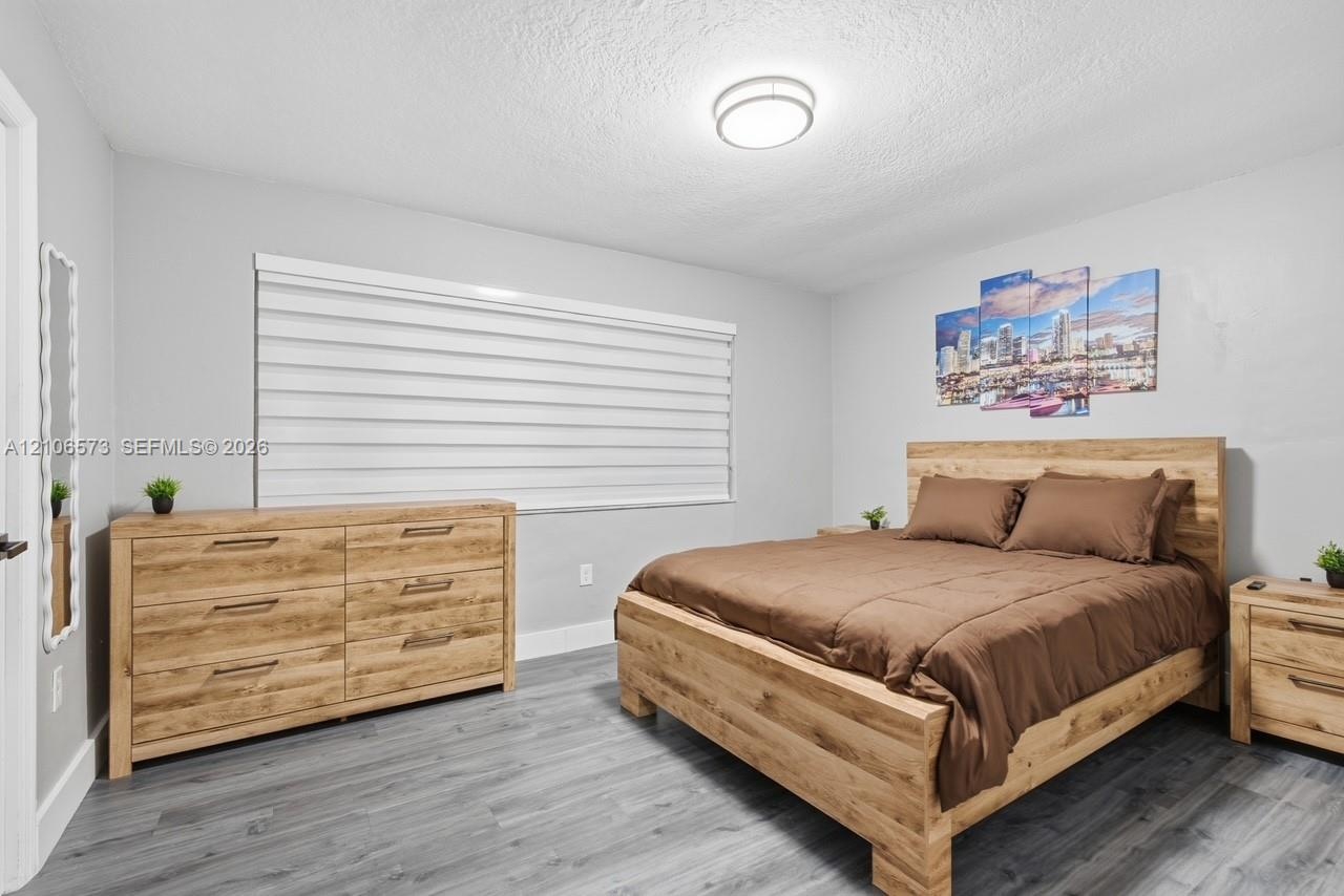 Room featuring neutral wall paint, wood-finish flooring, and a large horizontal window with integrated blinds, accented by a flush-mount ceiling light