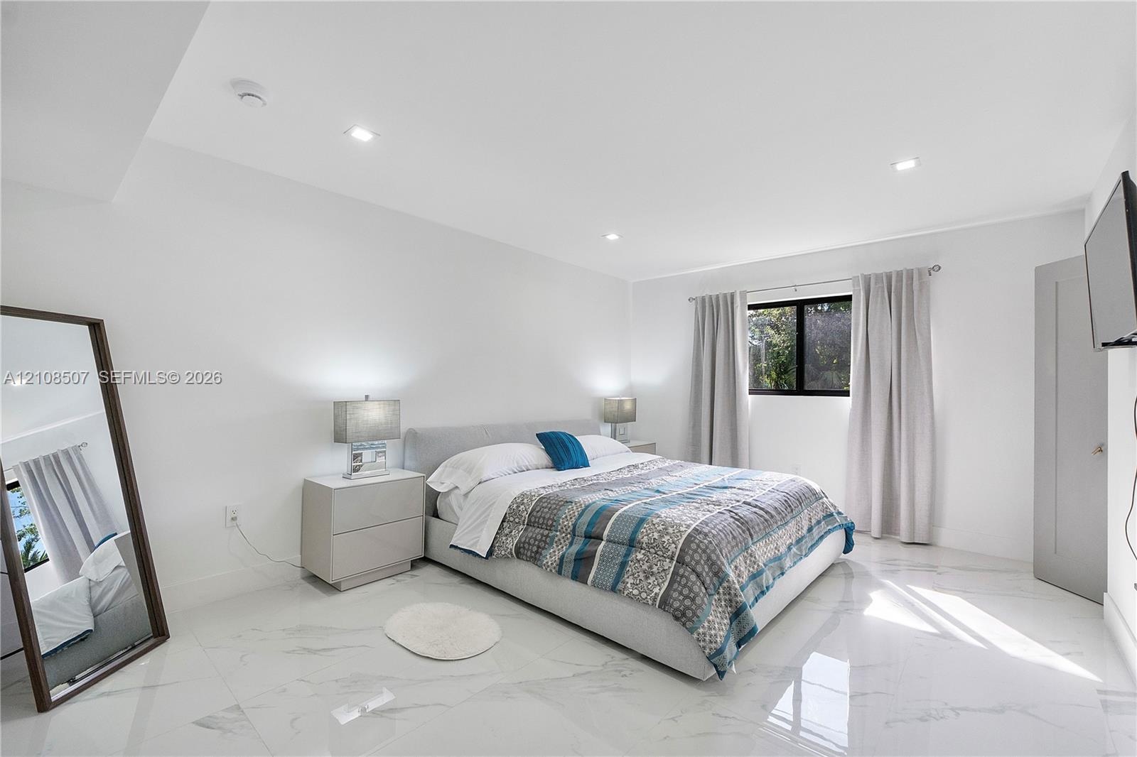 Large-format polished stone flooring, recessed ceiling lighting, and a single window with dark-toned framing