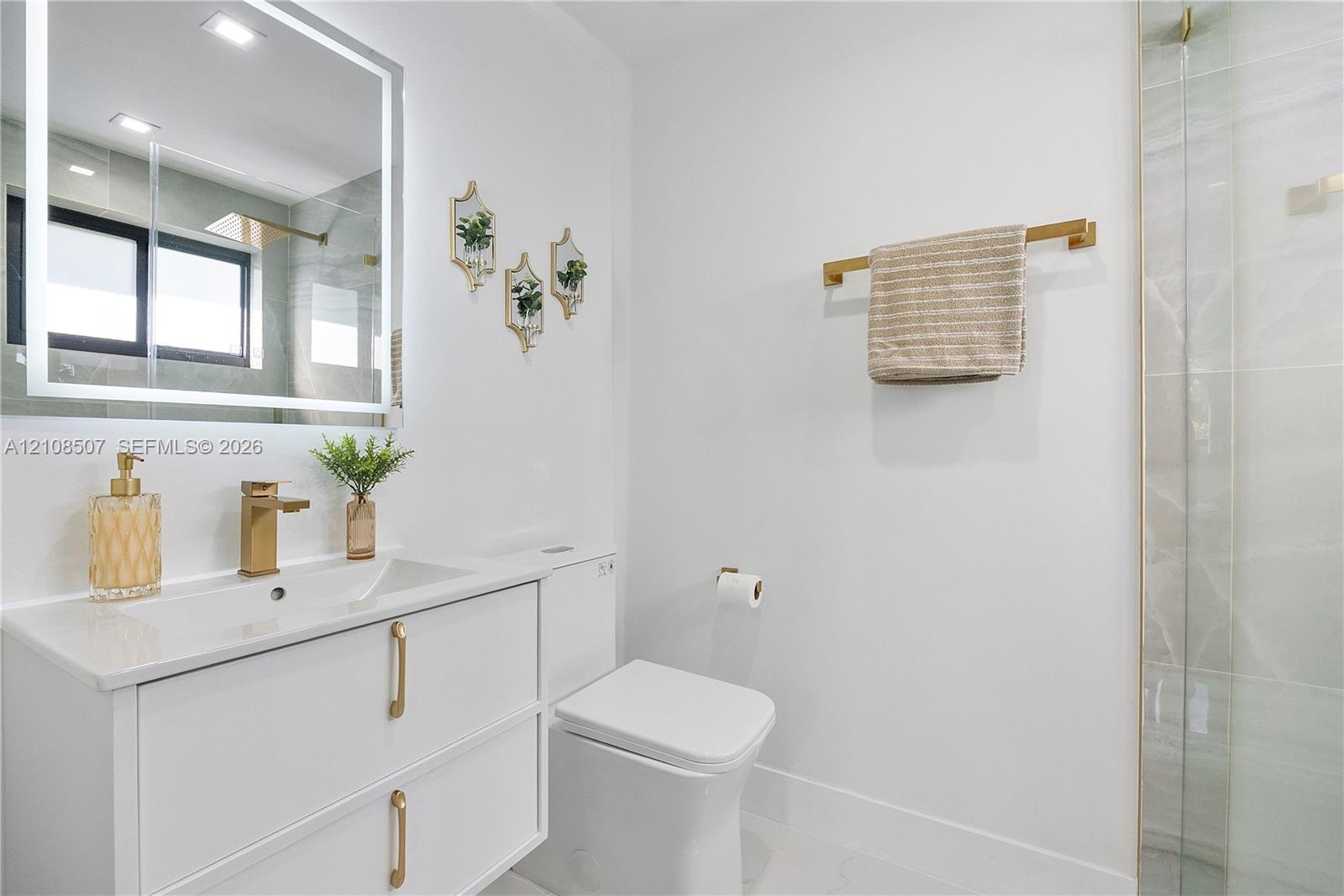 Modern floating vanity with a smooth countertop, integrated rectangular sink, and gold-finish hardware