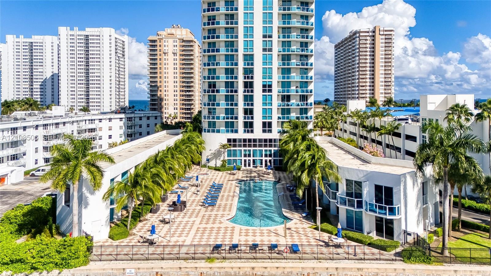 High-rise residential exterior featuring a paved pool deck, custom-shaped swimming pool, integrated landscaping, and private balconies
