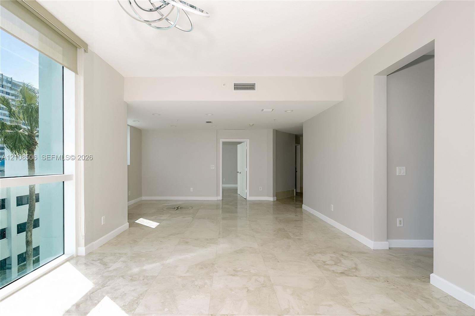 Floor-to-ceiling windows, polished stone tile flooring, modern circular chandelier, and recessed lighting