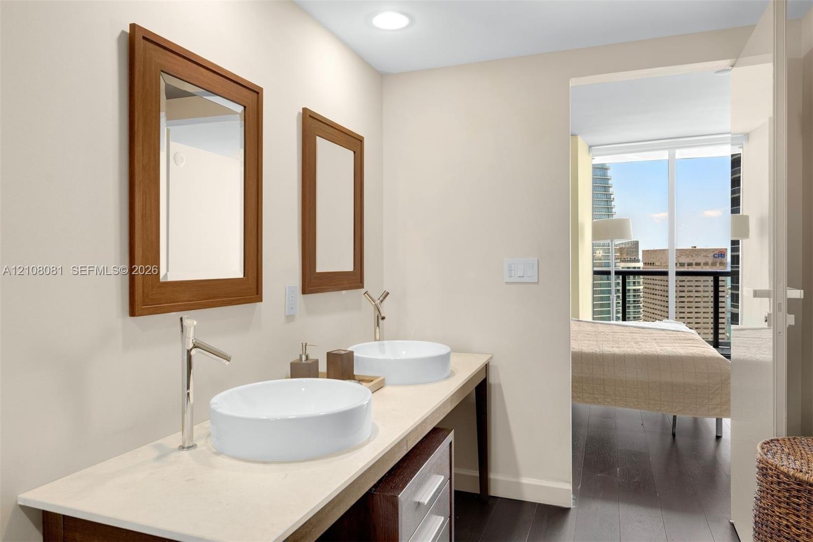 Dual-basin vanity featuring white vessel sinks, quartz countertops, chrome high-arc faucets, and wood-framed mirrors