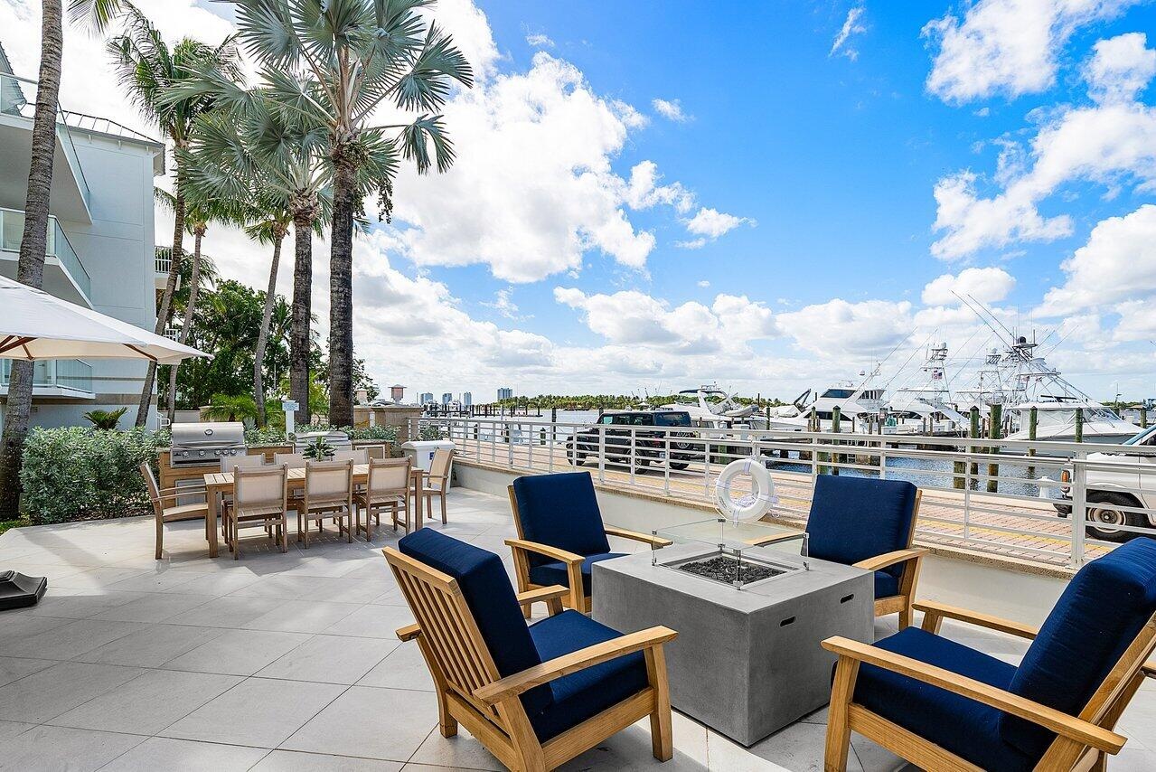 Waterfront stone patio featuring built-in outdoor kitchen, metal railing, and mature palm trees