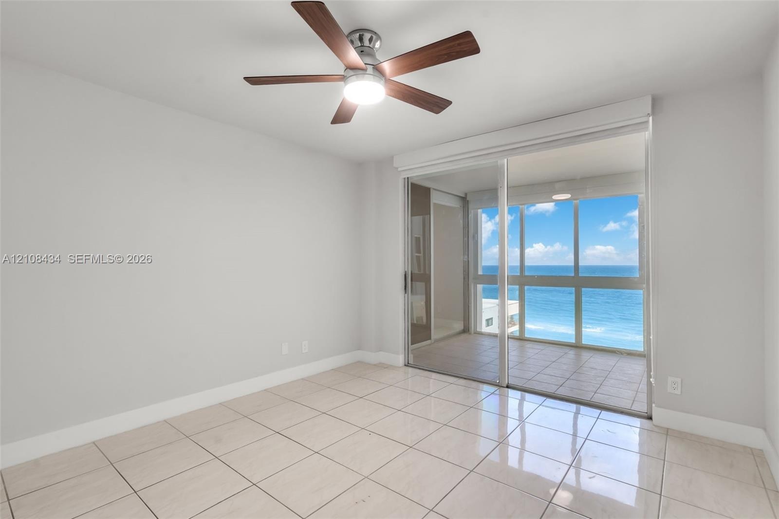 Interior space featuring large-format ceramic tile flooring, ceiling fan with integrated lighting, and full-height sliding glass doors opening to a ti
