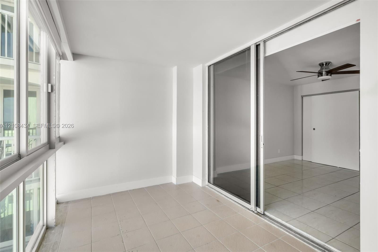 Enclosed sunroom featuring expansive multi-pane windows, large-format tile flooring, and a sliding glass door system