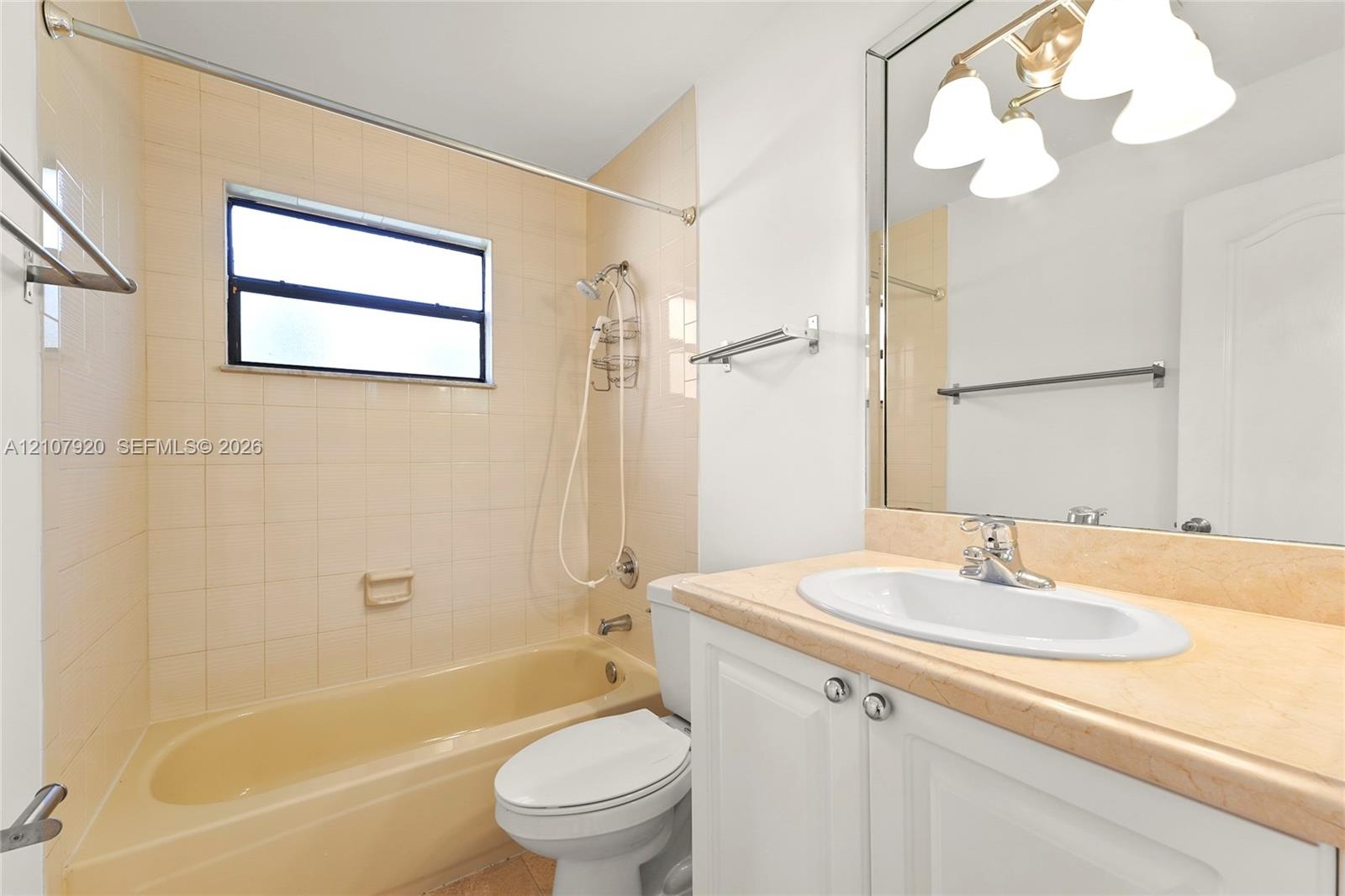 Bathroom featuring a neutral-toned tile shower surround, a built-in tub, a white vanity with a light-colored countertop, and a large-format mirror wit