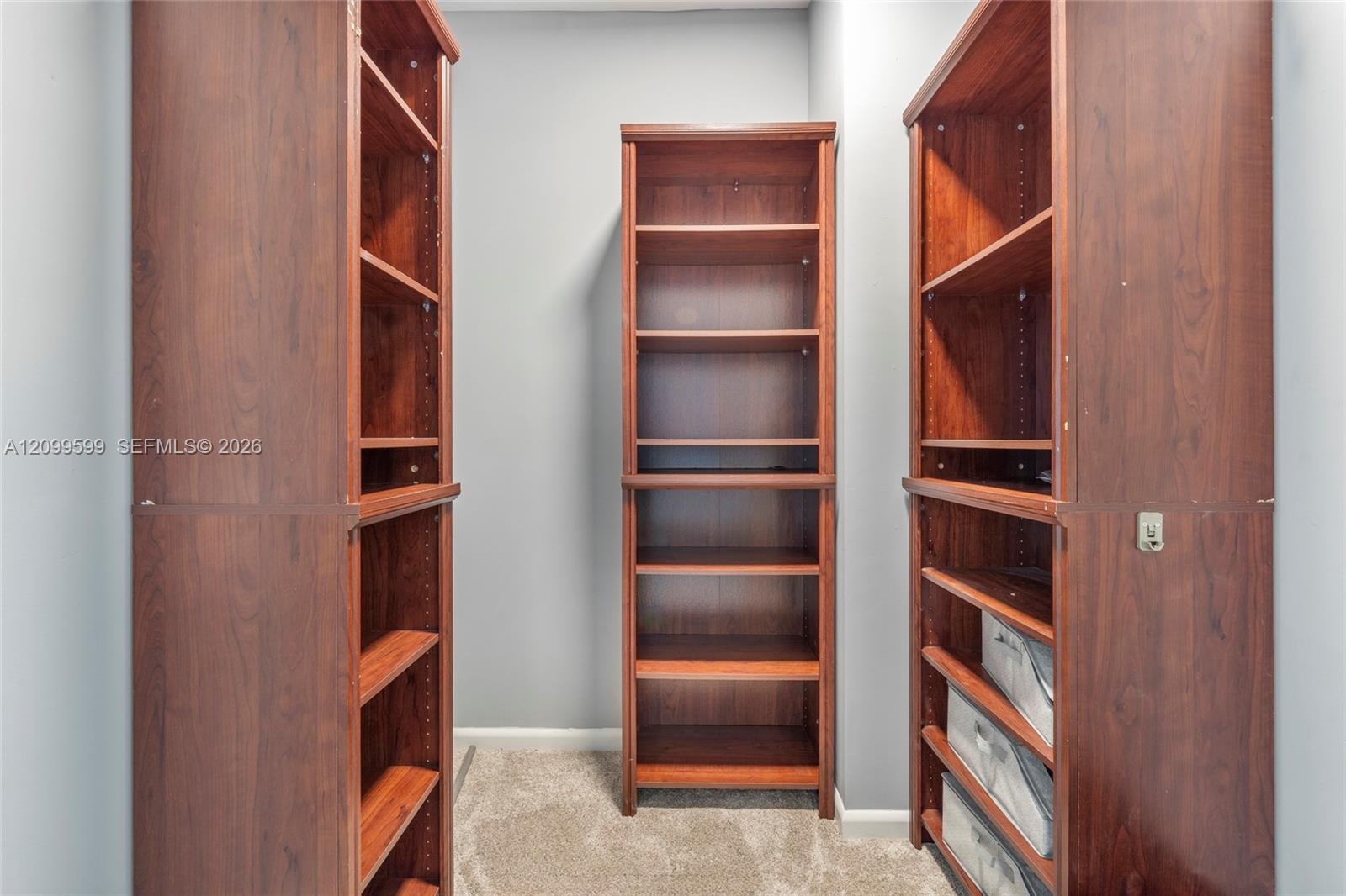Built-in floor-to-ceiling wood-finish shelving units with adjustable shelving and integrated slide-out storage drawers
