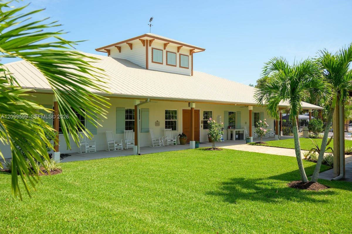 Single-story exterior featuring a metal roof, cupola with accent windows, wrap-around covered porch, and manicured landscaping