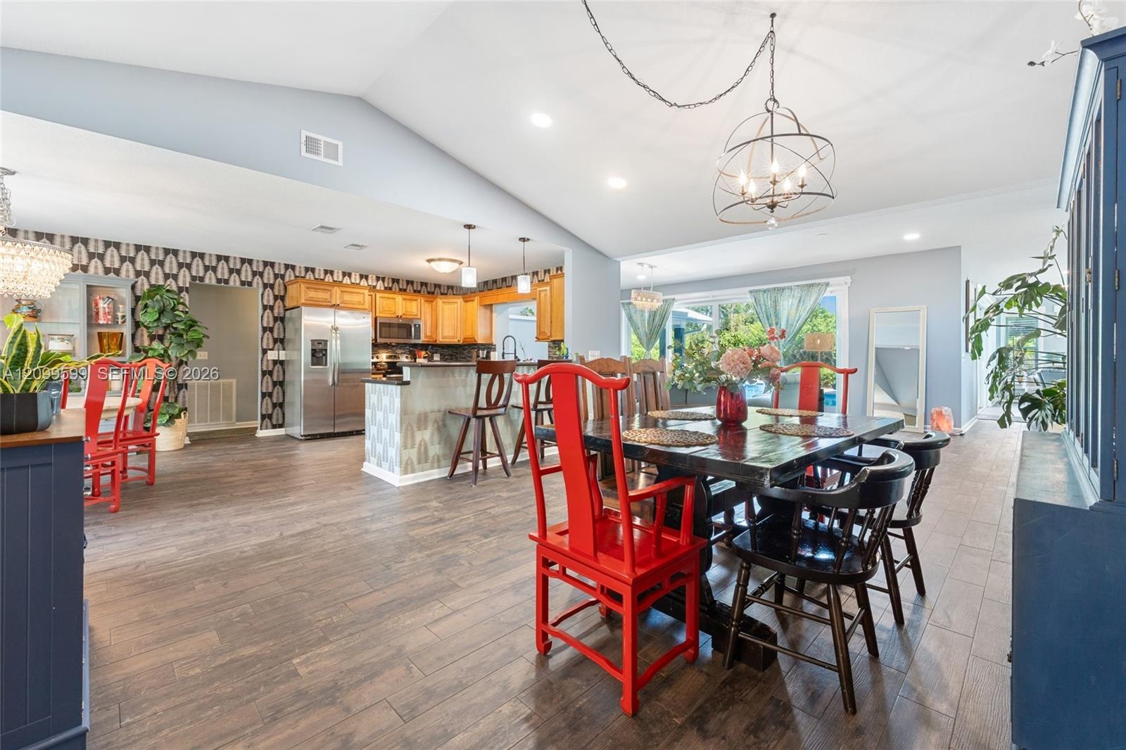 Open-concept interior featuring vaulted ceilings, wood-finish flooring, recessed lighting, and a kitchen peninsula with cabinetry