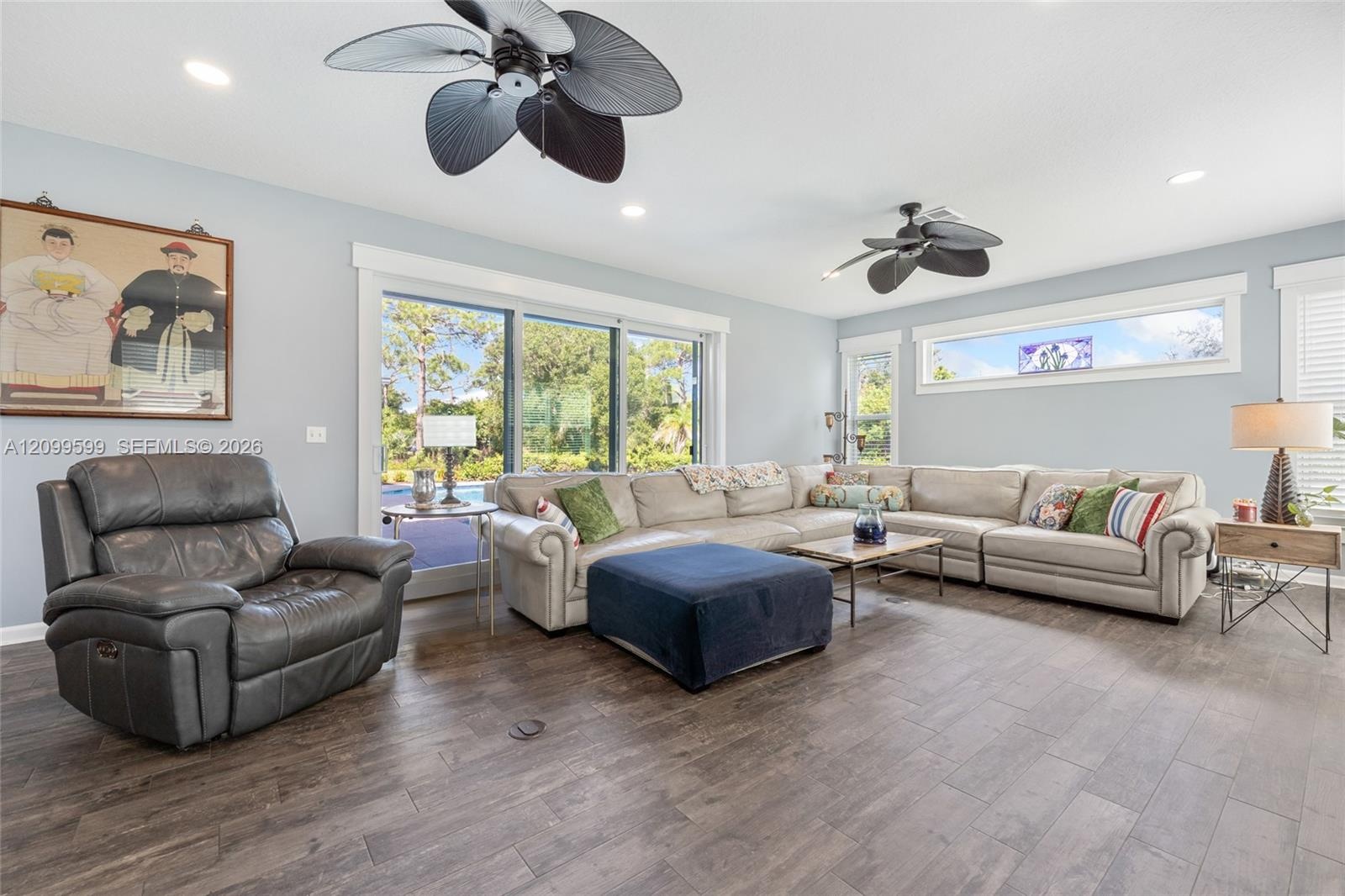 Living area featuring wood-finish flooring, two multi-blade ceiling fans, recessed lighting, and expansive sliding glass doors