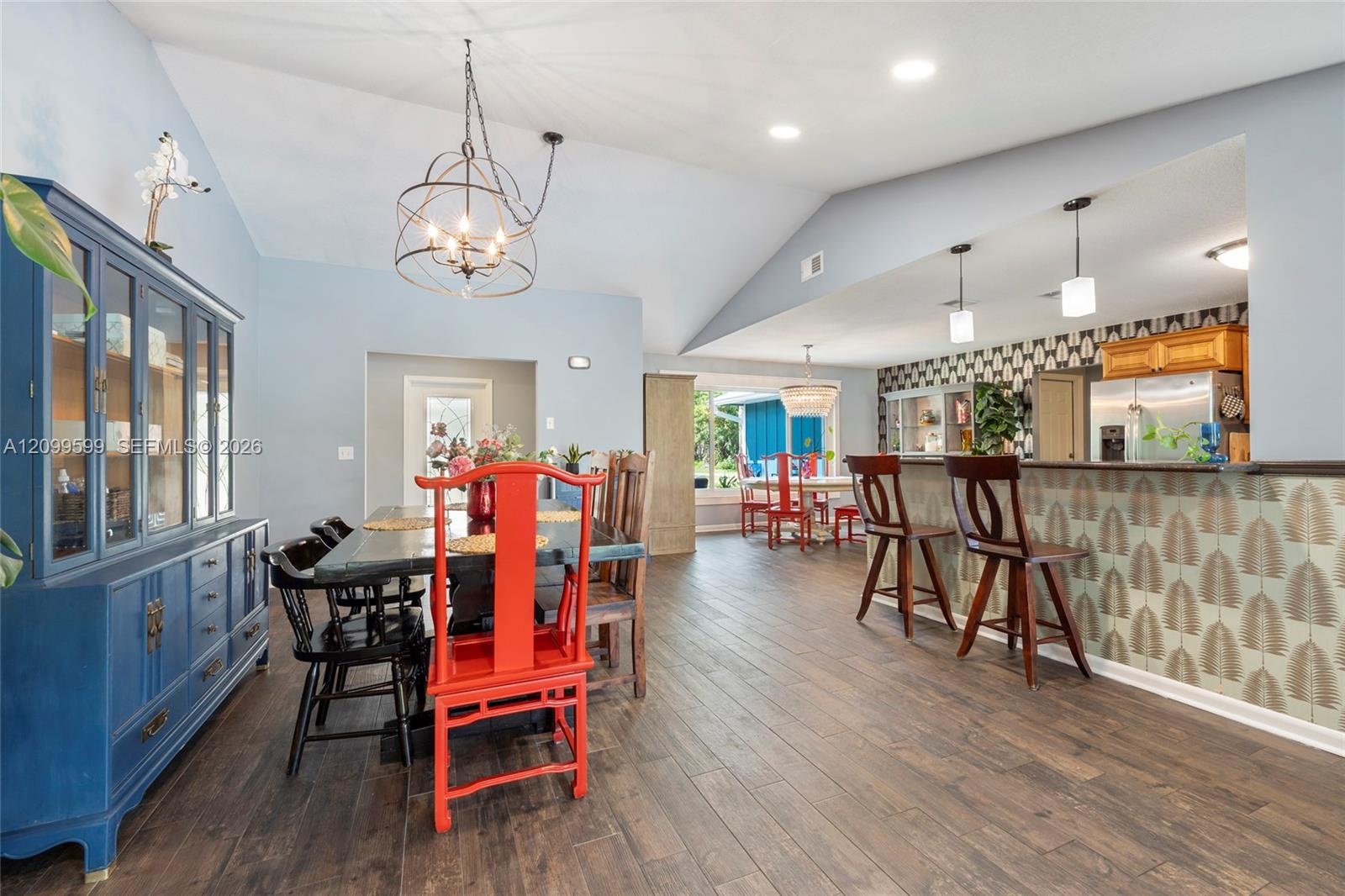Vaulted ceilings, wood-finish flooring, recessed lighting, metal globe chandelier, and kitchen peninsula with bar-style seating