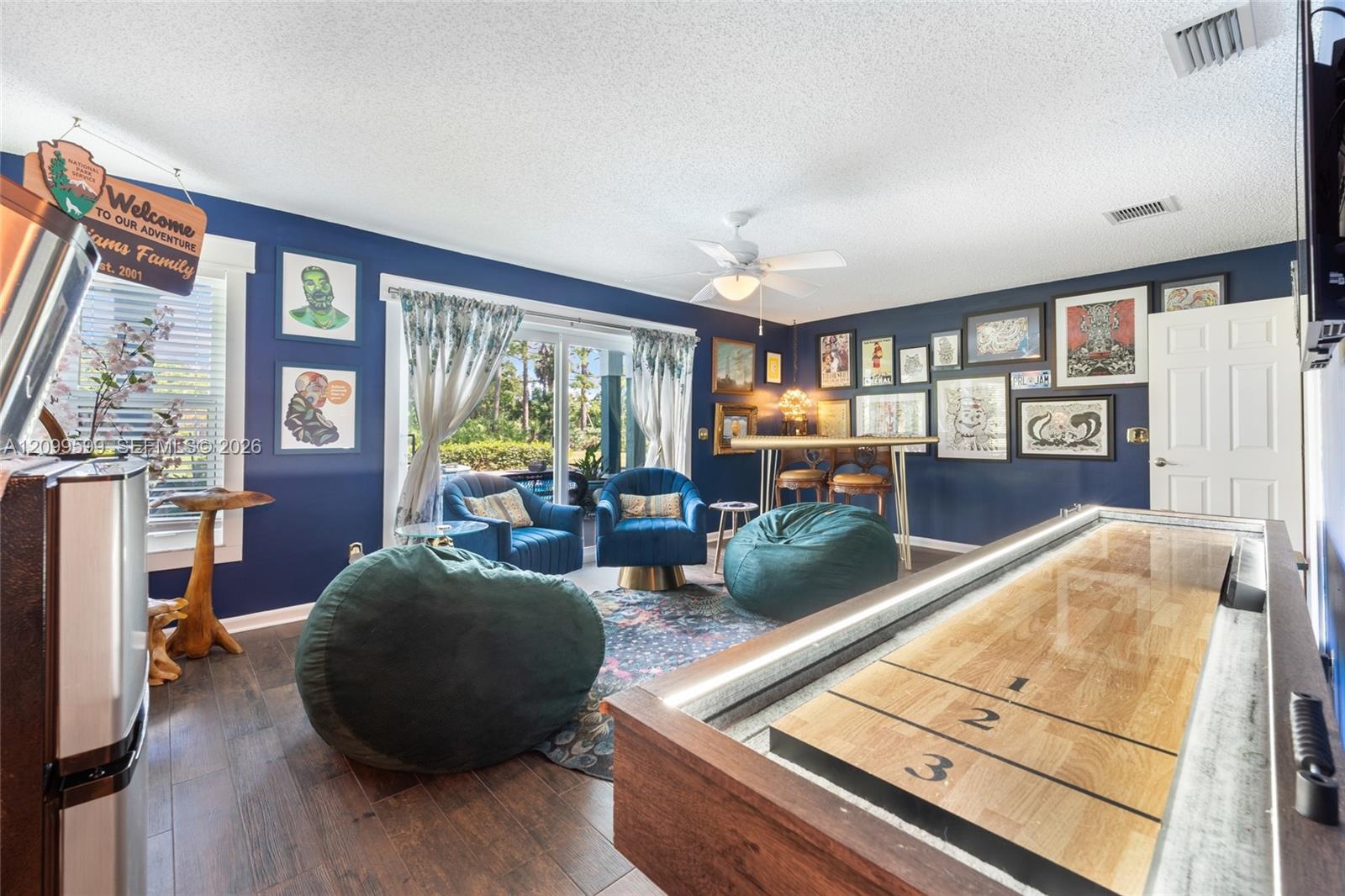 Interior space featuring wood-finish flooring, sliding glass doors, a ceiling-mounted light fixture with fan, and a six-panel interior door