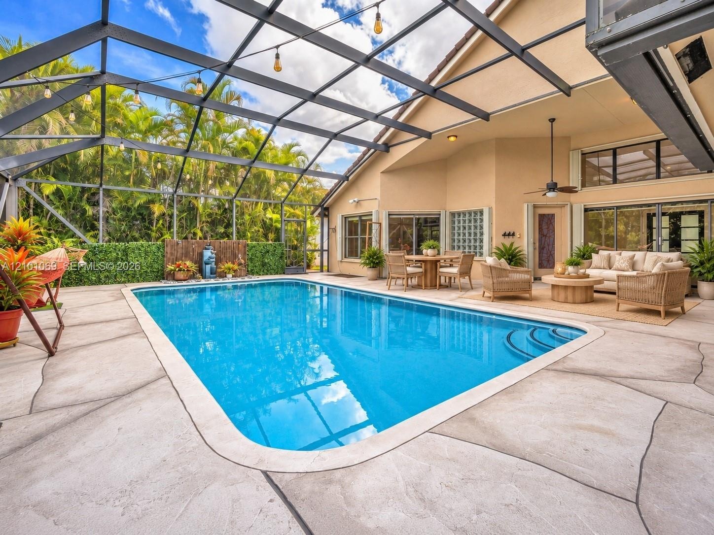 Screened-in patio featuring a concrete pool deck with decorative scoring, a rectangular swimming pool with built-in stairs, and string lighting