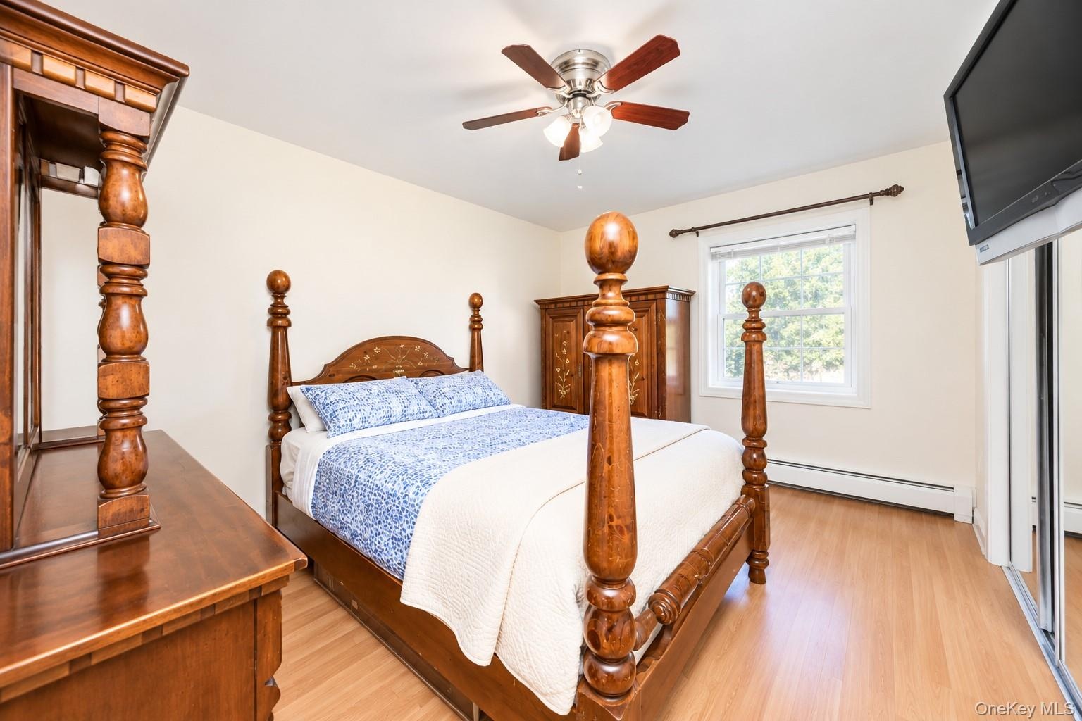 Wood-finish flooring, ceiling fan with integrated lighting, and mirrored sliding closet doors