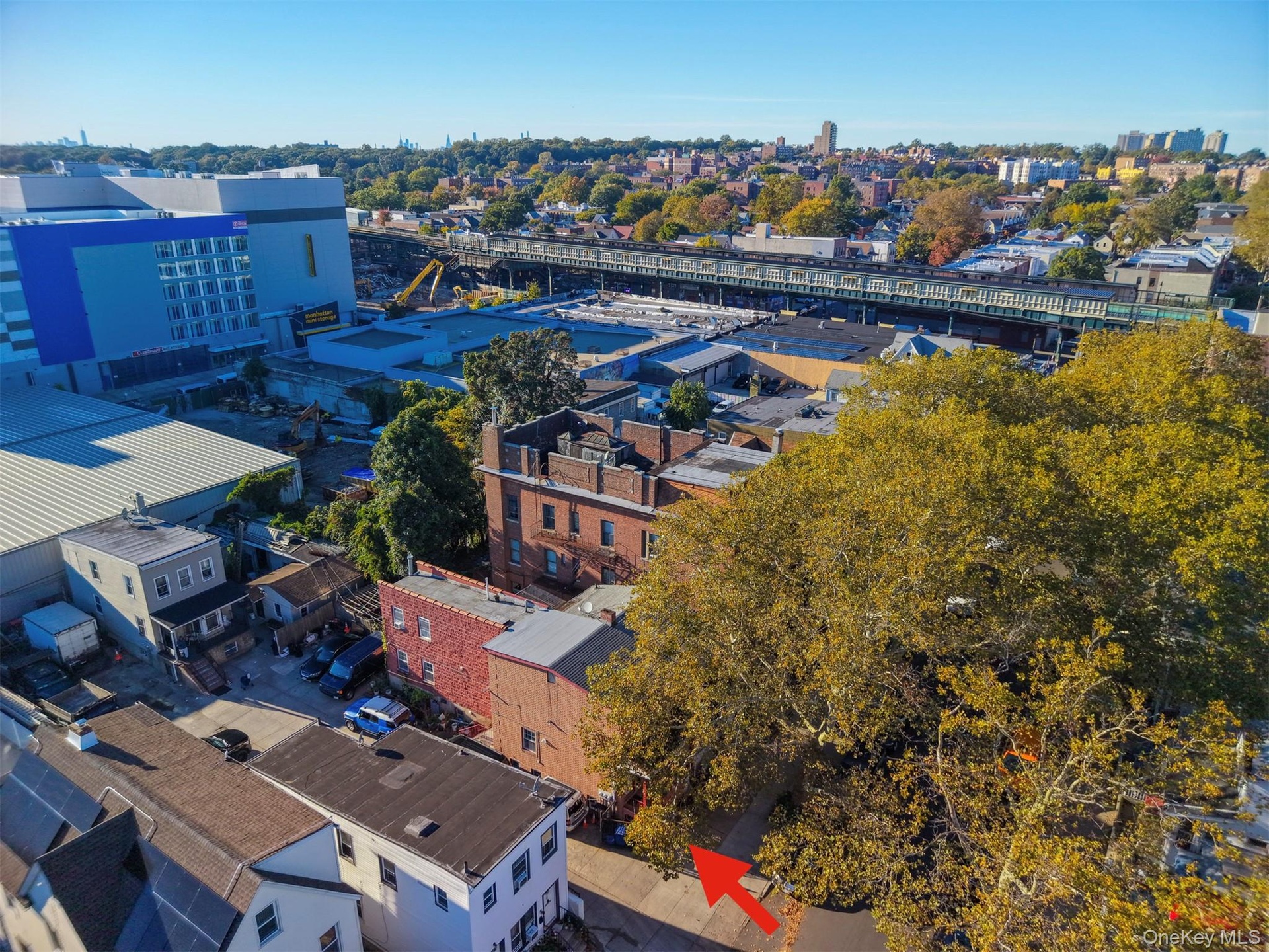 Aerial perspective featuring an urban landscape with mature trees and a prominent brick-exterior structure