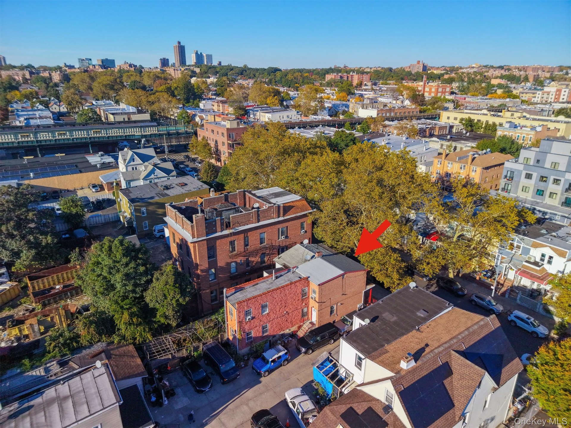 Aerial perspective of a multi-story masonry building with a flat roofline situated in an established urban setting featuring mature tree cover