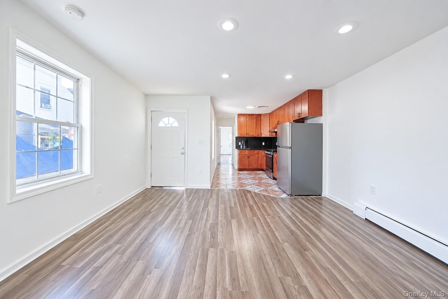 Open floor plan featuring wood-finish flooring, recessed lighting, and kitchen cabinetry with integrated appliances