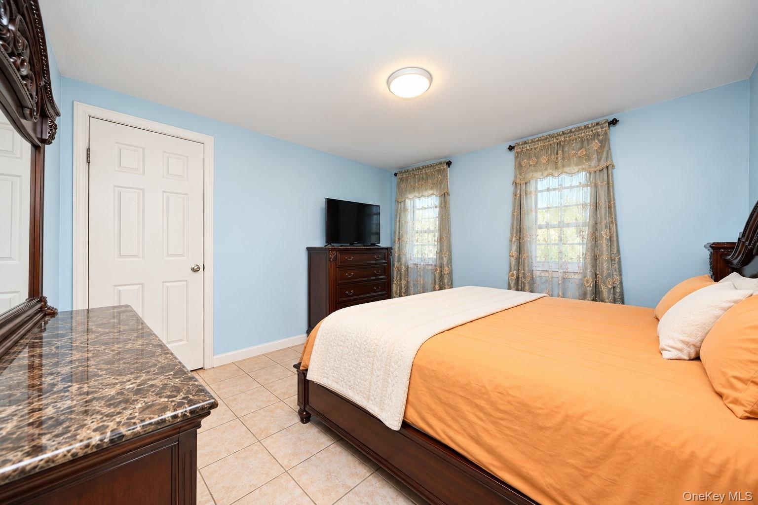 Neutral tile flooring, multi-panel interior door, and dual windows with grid detailing