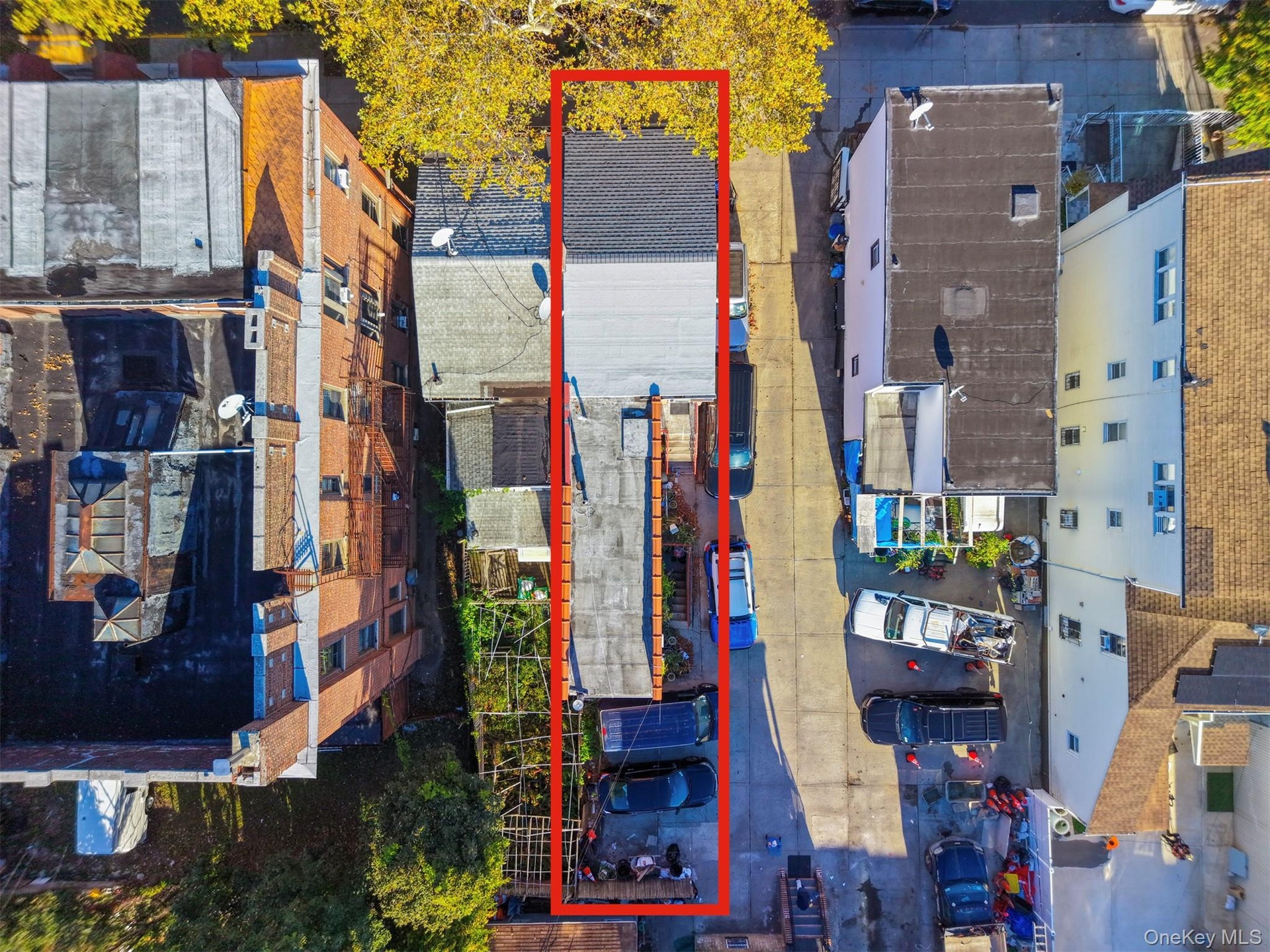 Aerial perspective of property lot featuring a rear paved parking area and a rectangular building footprint with a pitched shingle roof