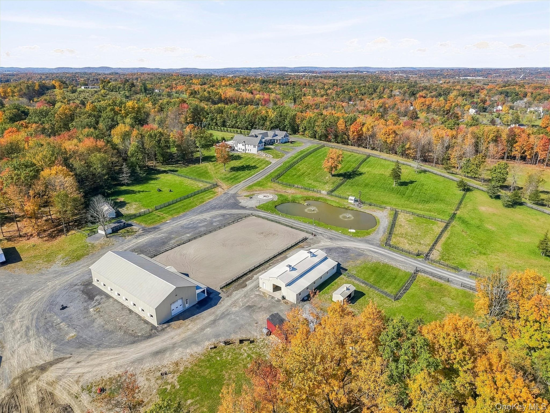 Extensive acreage featuring a large outdoor riding arena, a private pond, multiple outbuildings, and fenced pastures