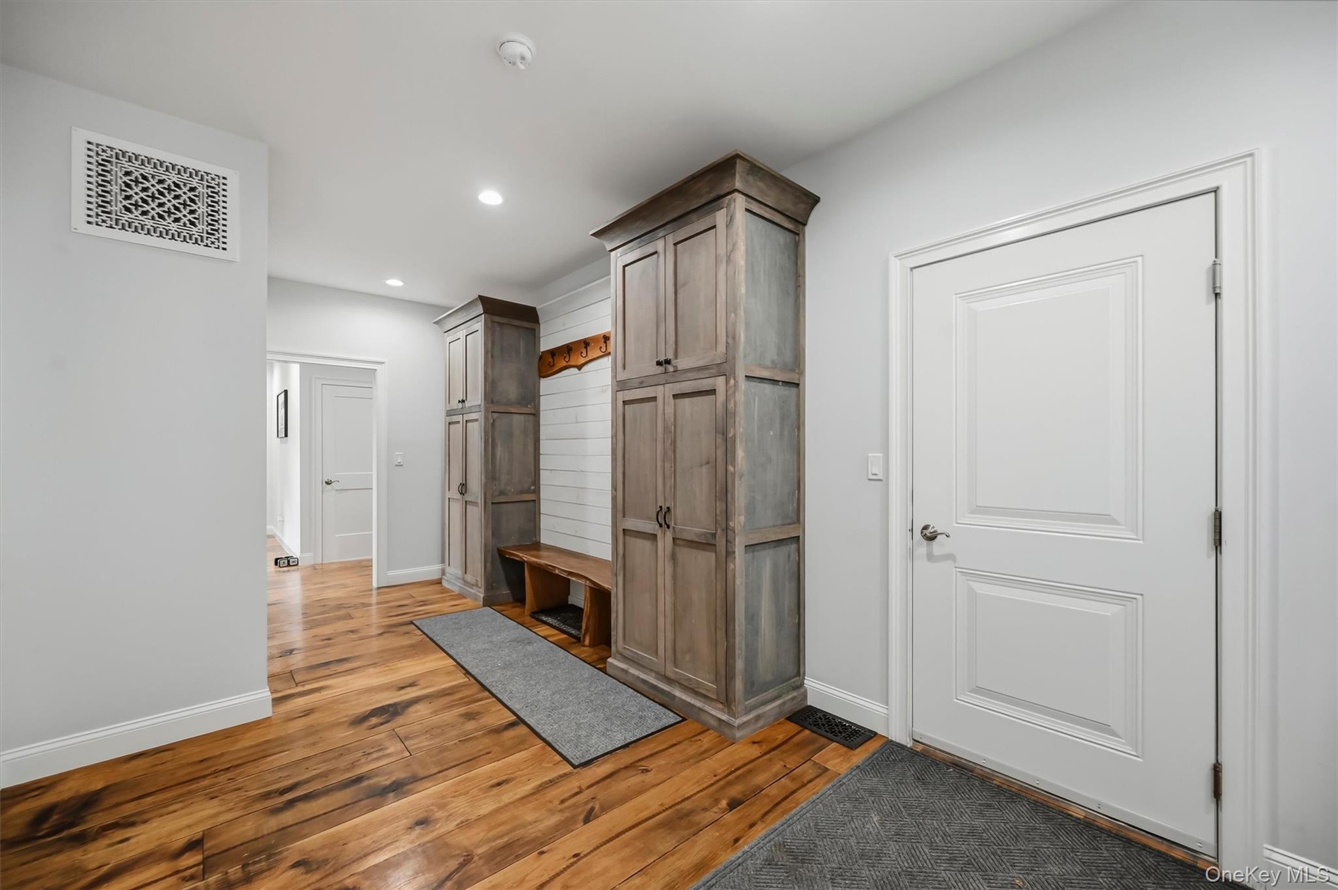 Custom-built cabinetry with wood-finish doors, integrated bench seating, horizontal shiplap wall paneling, and wide-plank wood-finish flooring