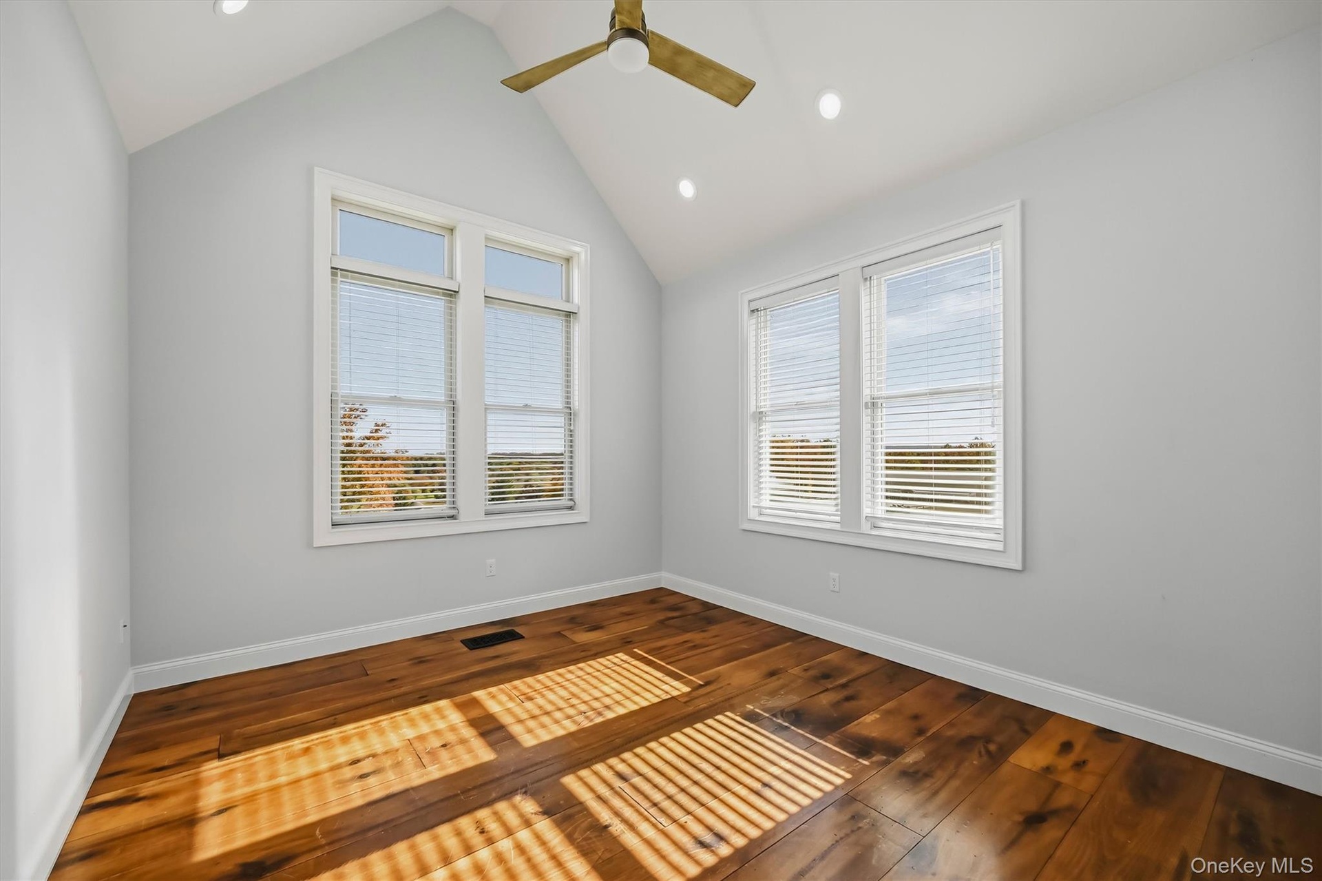 Vaulted ceiling with recessed lighting, wood-finish flooring, and expansive windows