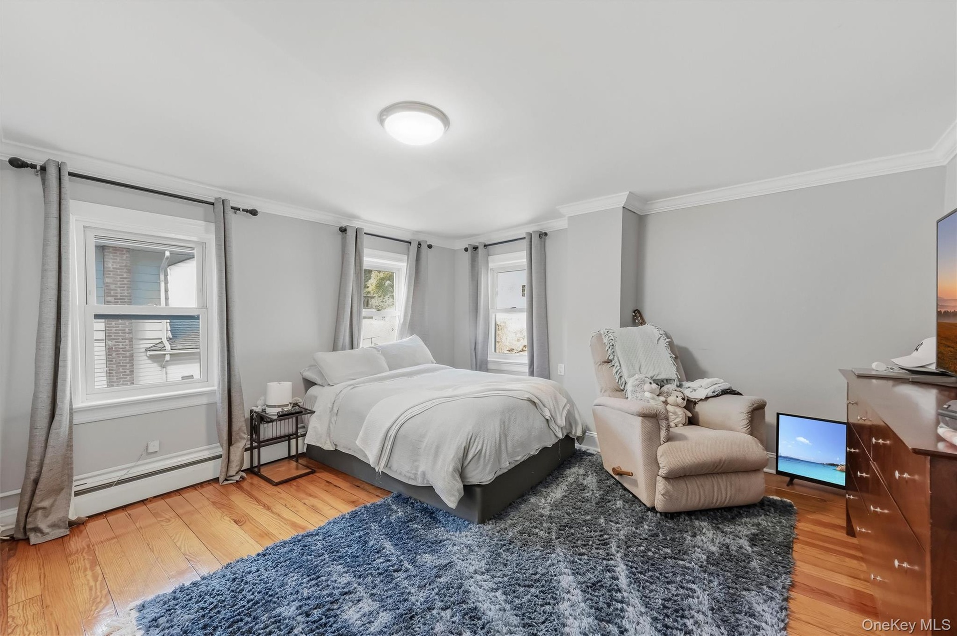 Spacious bedroom filled with natural light, featuring gleaming hardwood floors and a peaceful, inviting atmosphere.