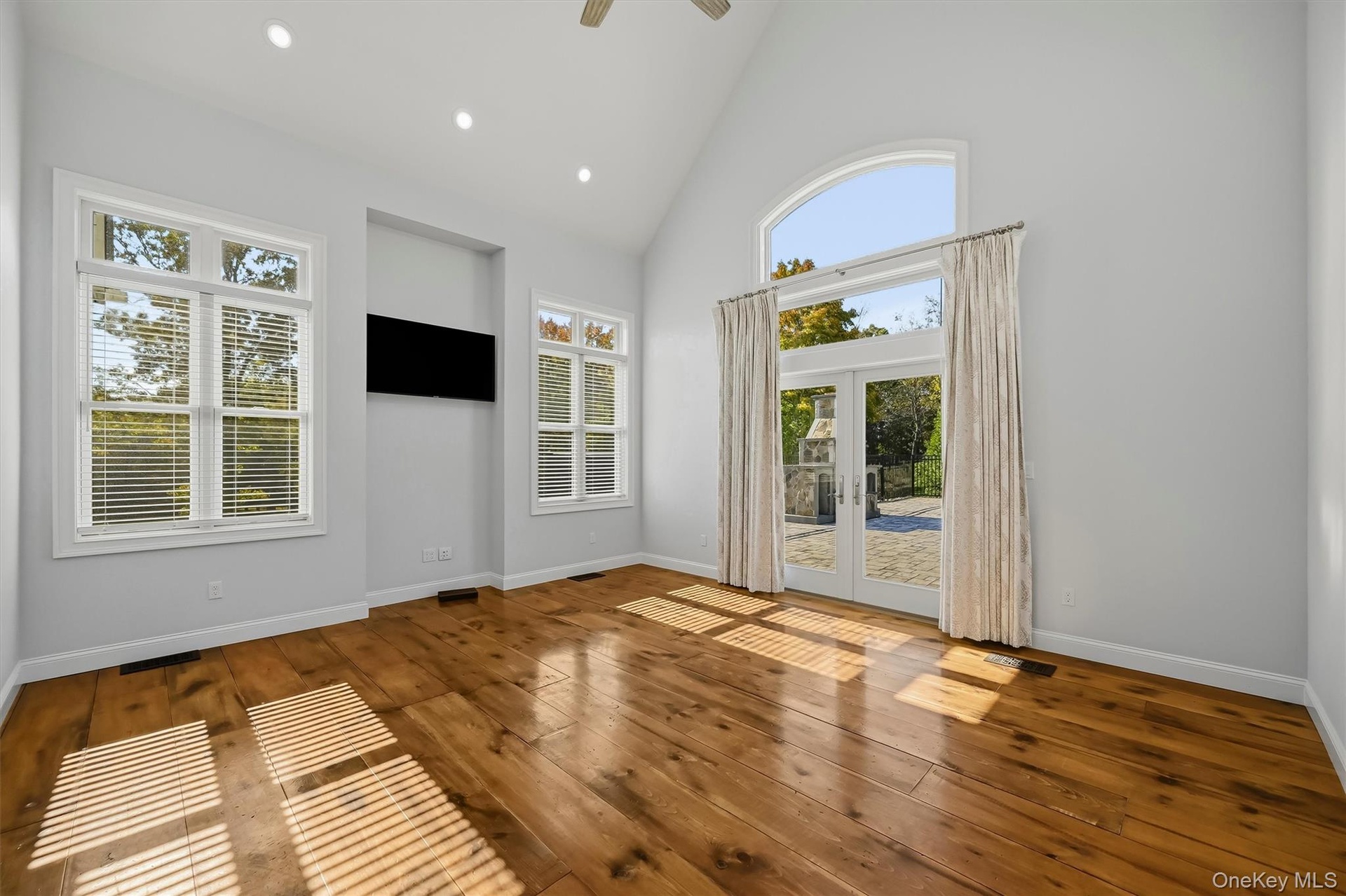 Sundrenched spacious bedroom with French doors leading ton patio andnpool