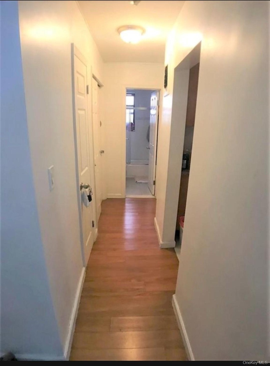 Corridor with light wood-type flooring and baseboards