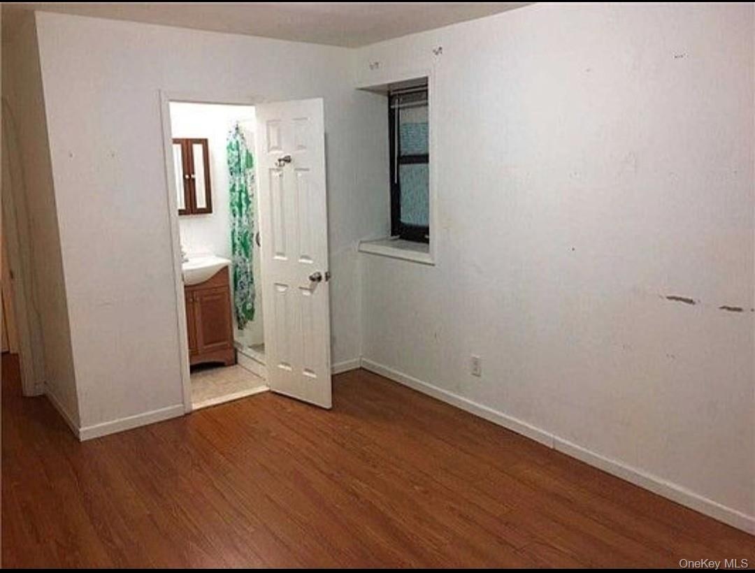 Unfurnished bedroom featuring dark wood-style floors and ensuite bath