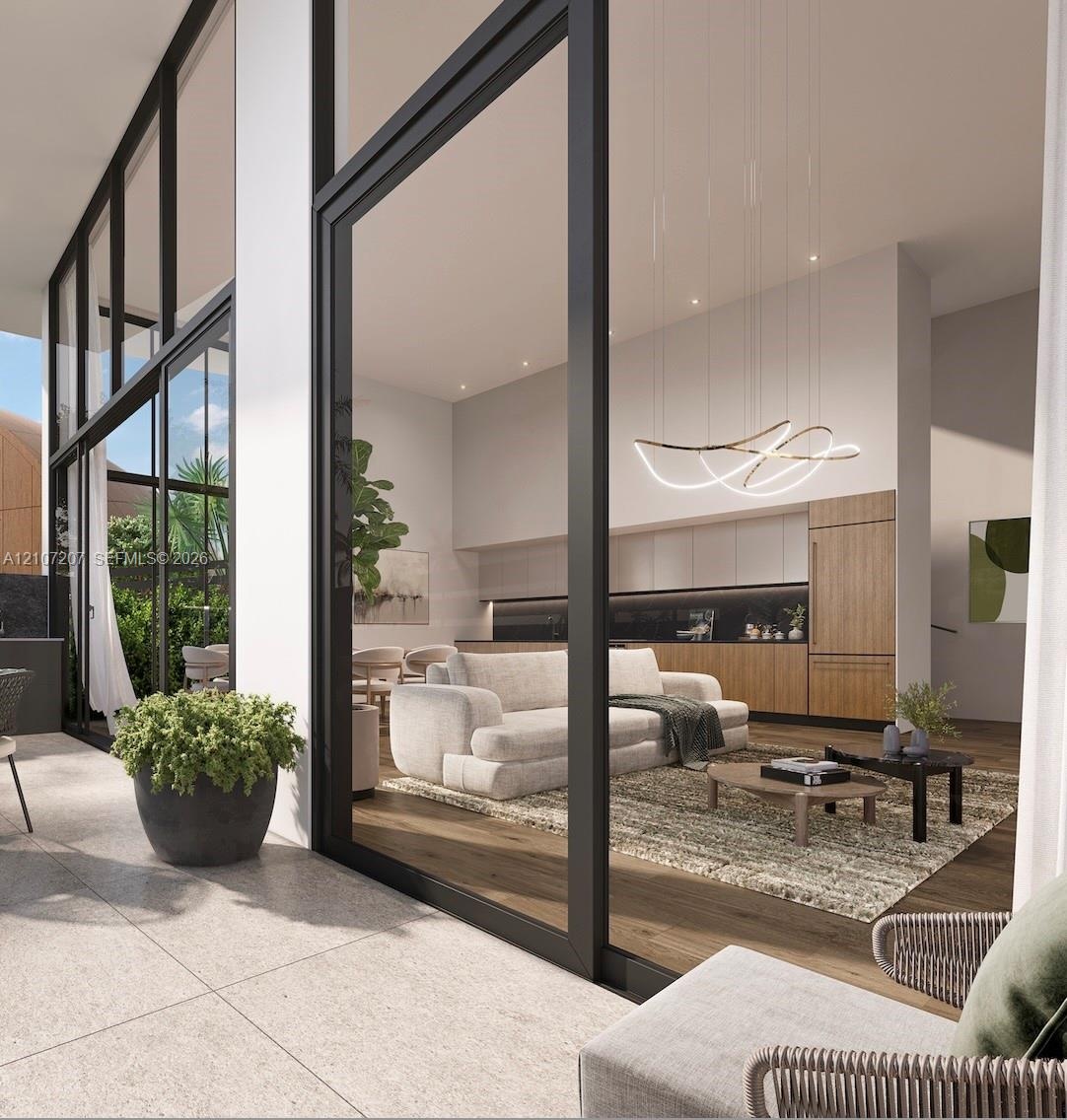 Floor-to-ceiling glass wall panels with black framing, wood-finish flooring, custom wood-veneer cabinetry, recessed ceiling lighting, and sculptural L