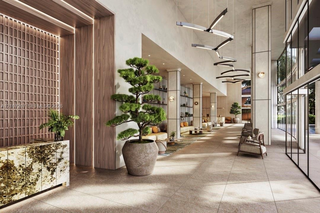 Grand lobby featuring high ceilings, stone tile flooring, geometric light fixtures, wood-paneled accent wall with integrated lighting, and a stone-cla