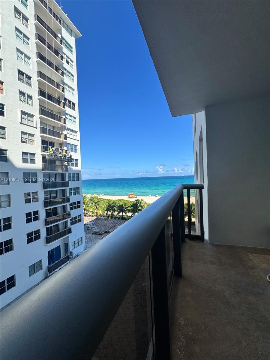 Private balcony featuring a metal and glass railing, concrete flooring, and an expansive ocean backdrop
