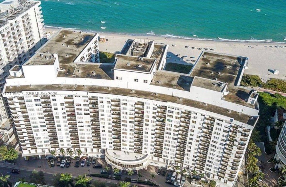 High-rise residential building featuring expansive balcony tiers, direct proximity to the shoreline, and a circular ground-level porte-cochere