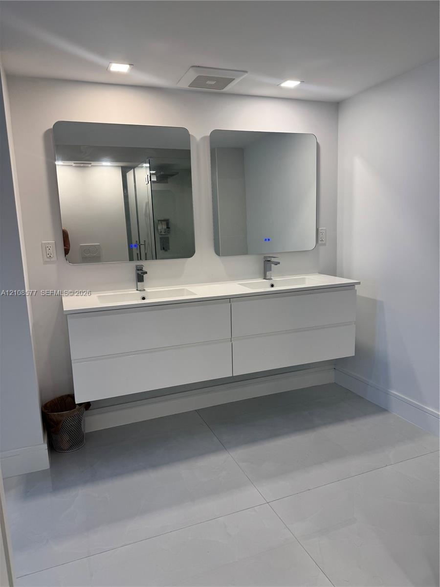 Double floating vanity featuring a white composite countertop, dual integrated sinks, chrome faucets, and two rectangular wall-mounted mirrors with in