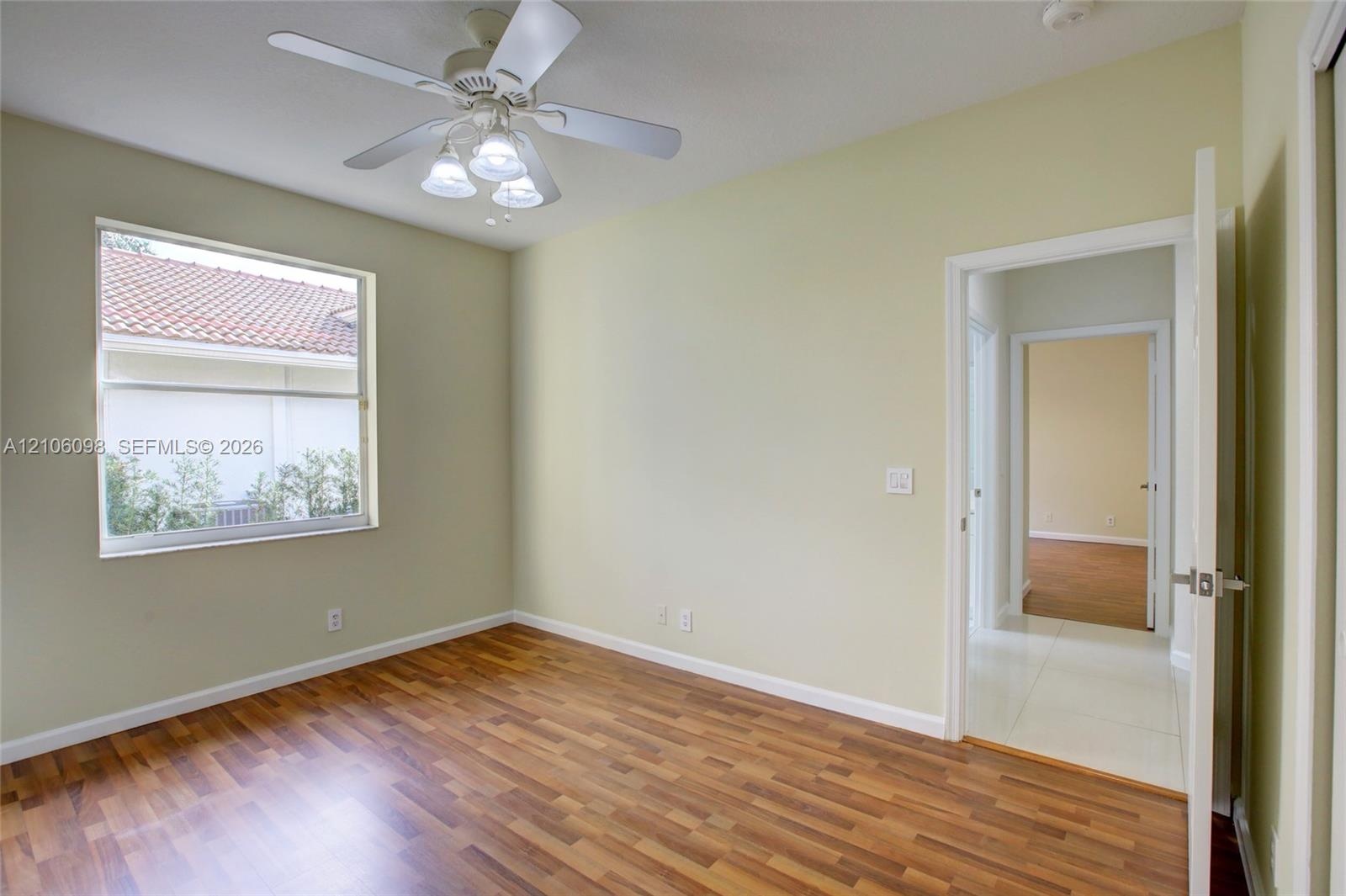 Room featuring wood-finish flooring, a multi-light ceiling fan, and a single-pane window